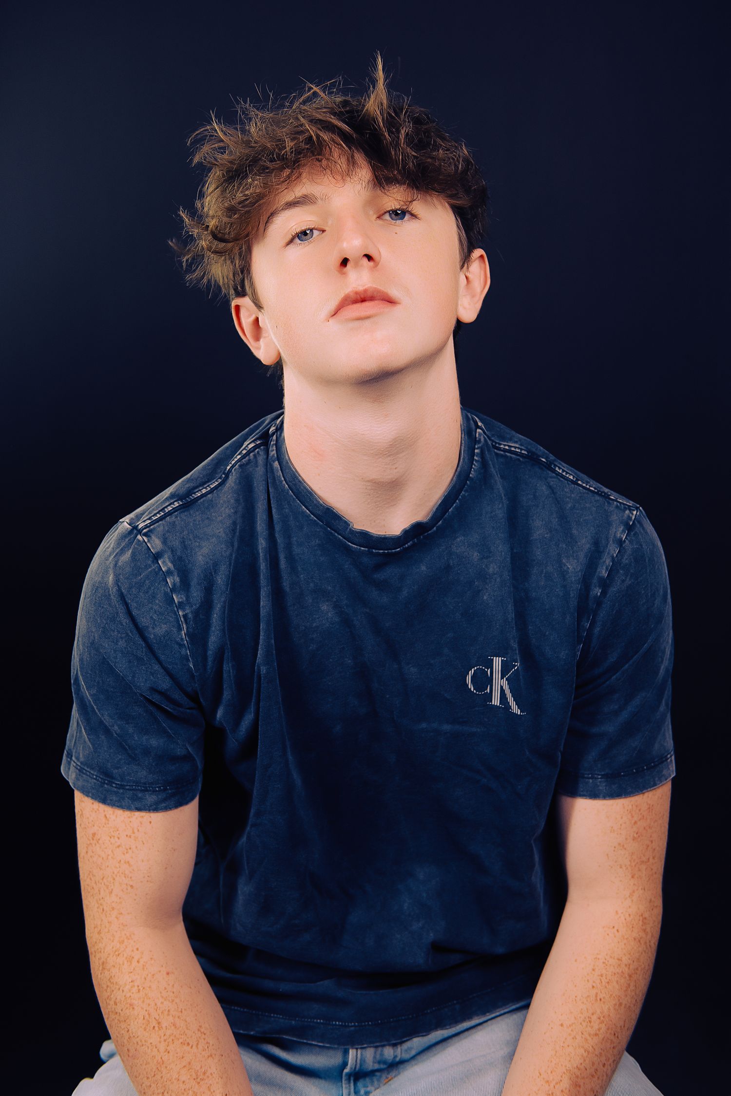 Studio portraits against dark background featuring casual denim styling.