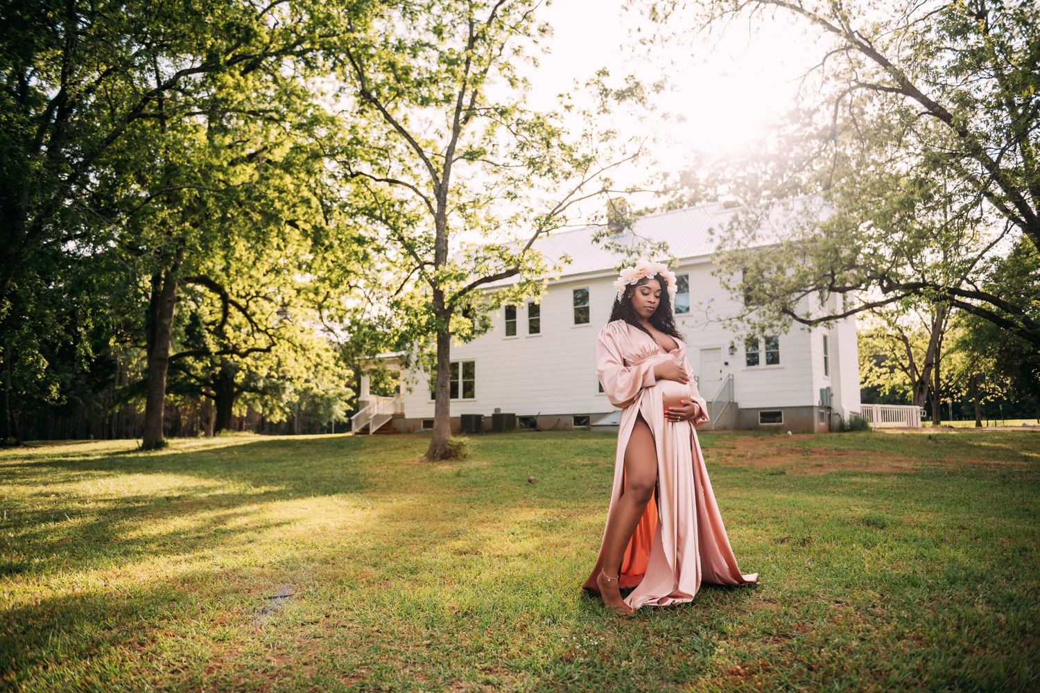 Ethereal outdoor photoshoot in sunlit field with flowing pink dress.