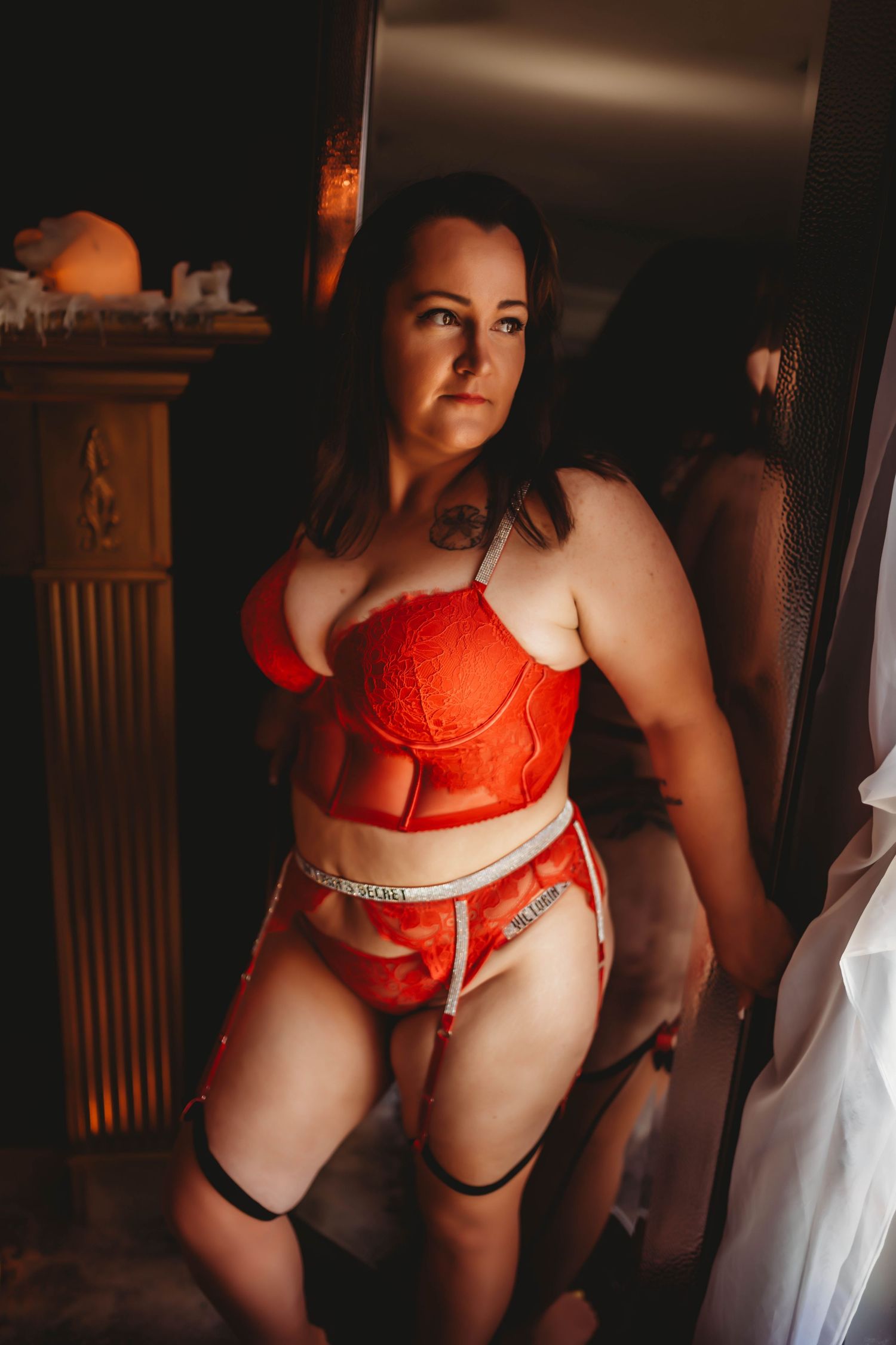 Red lace lingerie captured in moody boudoir photography with dramatic shadows.