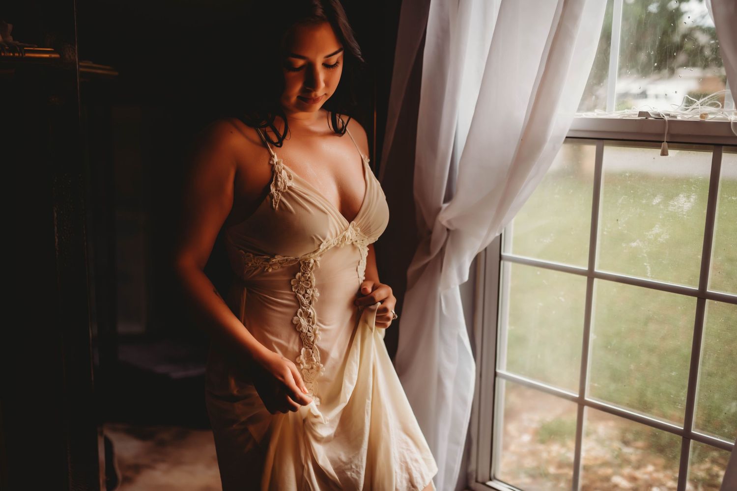Elegant bridal portrait with flowing champagne dress next to sunlit window.