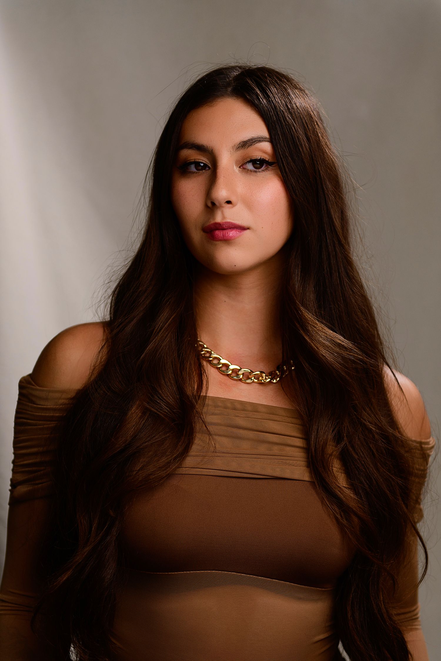 A series of fashion portraits showing a figure in a brown sleeveless top with long dark hair and a gold chain necklace.