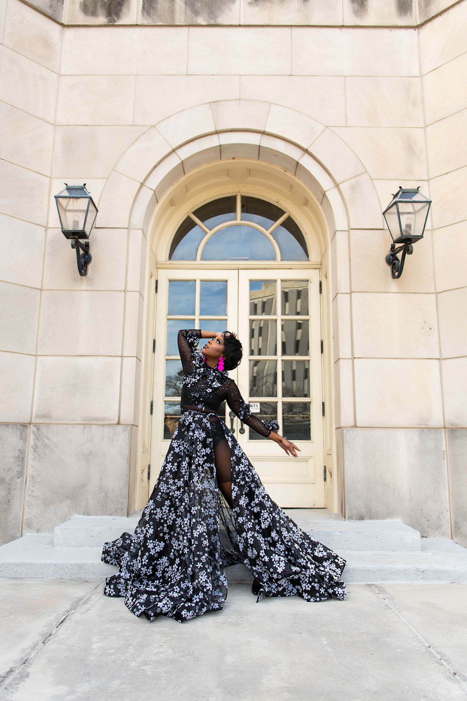 A black and white floral ballgown dress photographed in sequence against a white stone building exterior.