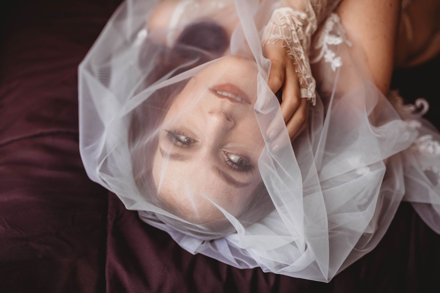 Dreamy portrait through sheer fabric creating ethereal effect.