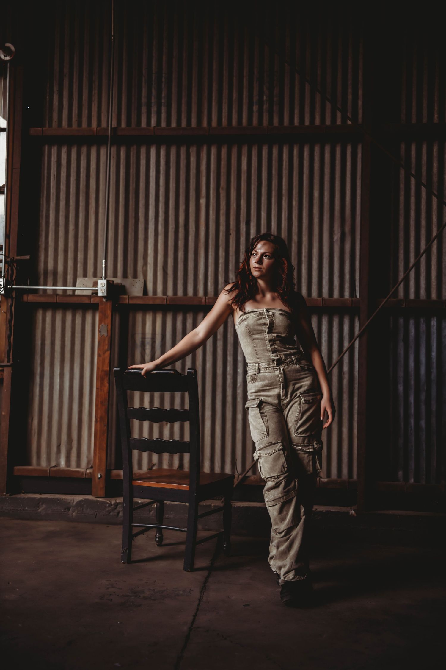 Fashion portrait in cargo pants against industrial metal wall setting.