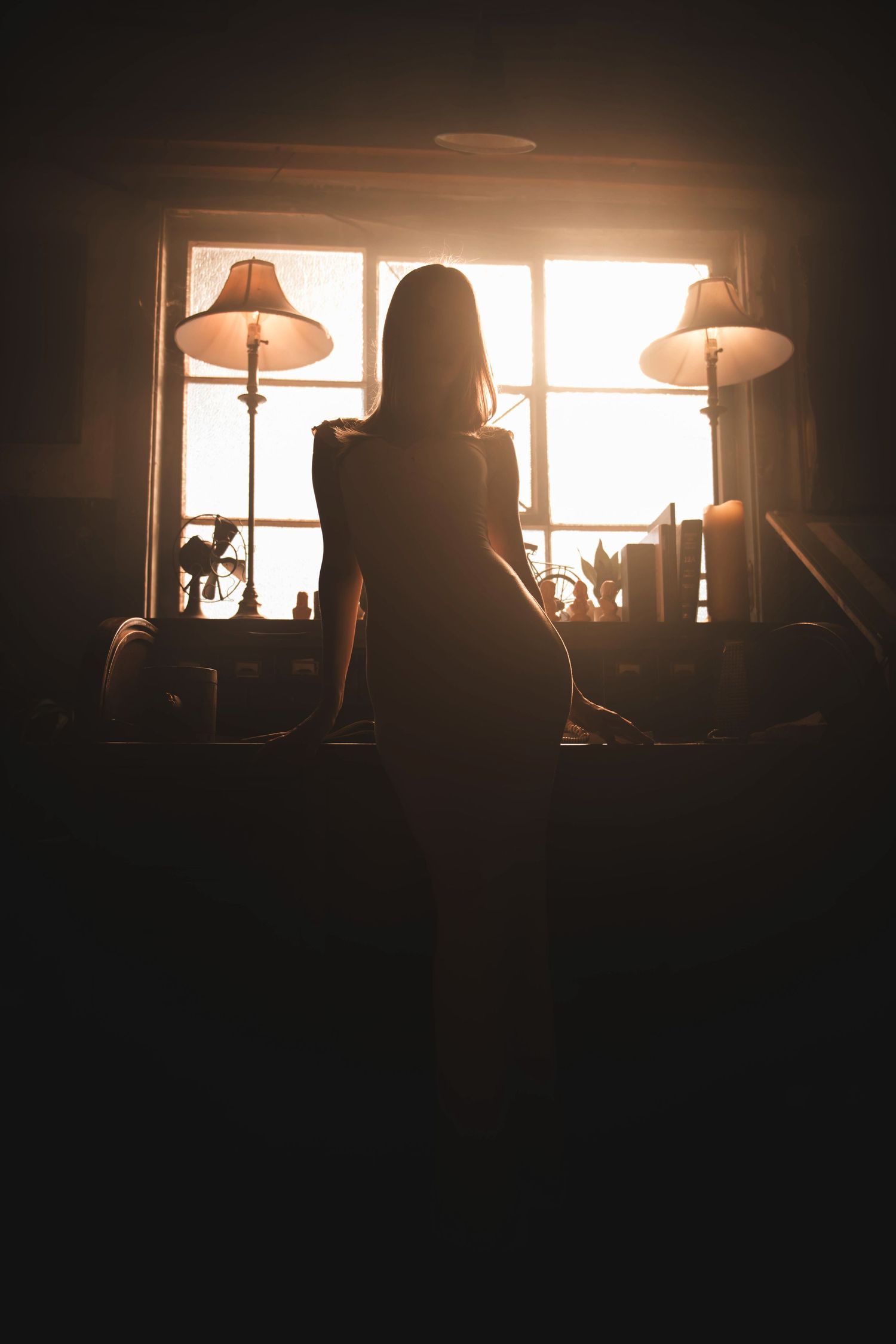 Silhouetted window scene at sunset with warm backlighting creating dramatic shadows.
