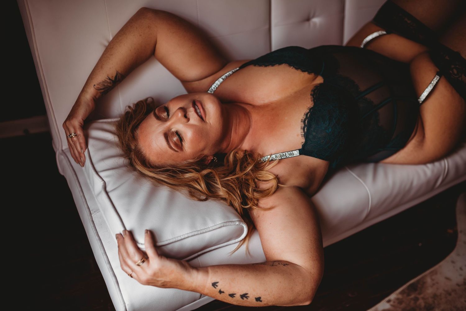 Intimate portrait session on light colored furniture with dramatic lighting.