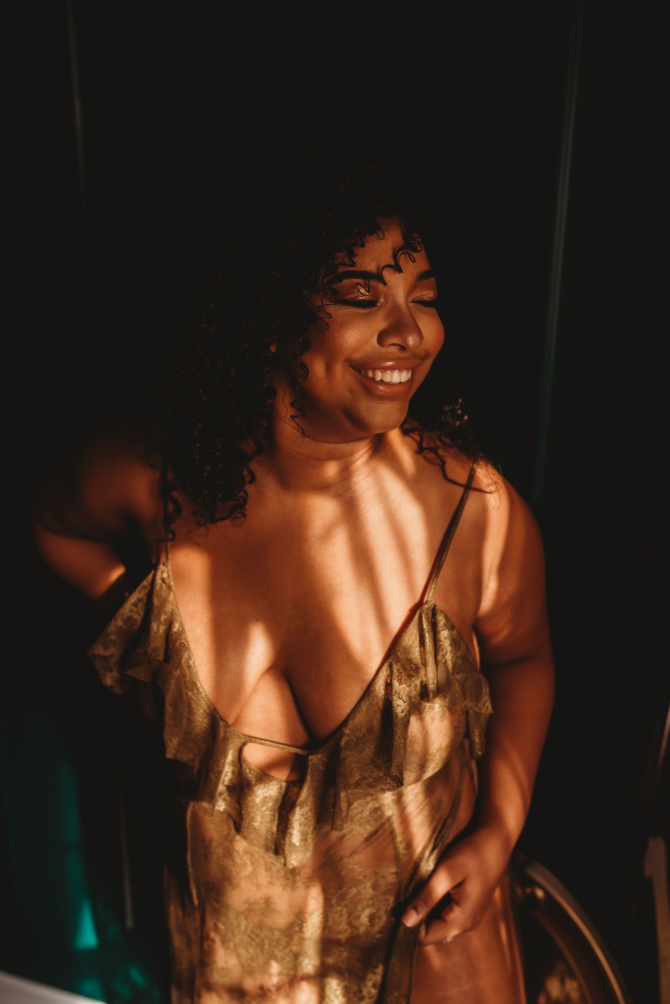 Soft glow illuminates figure in gold dress against dark background.