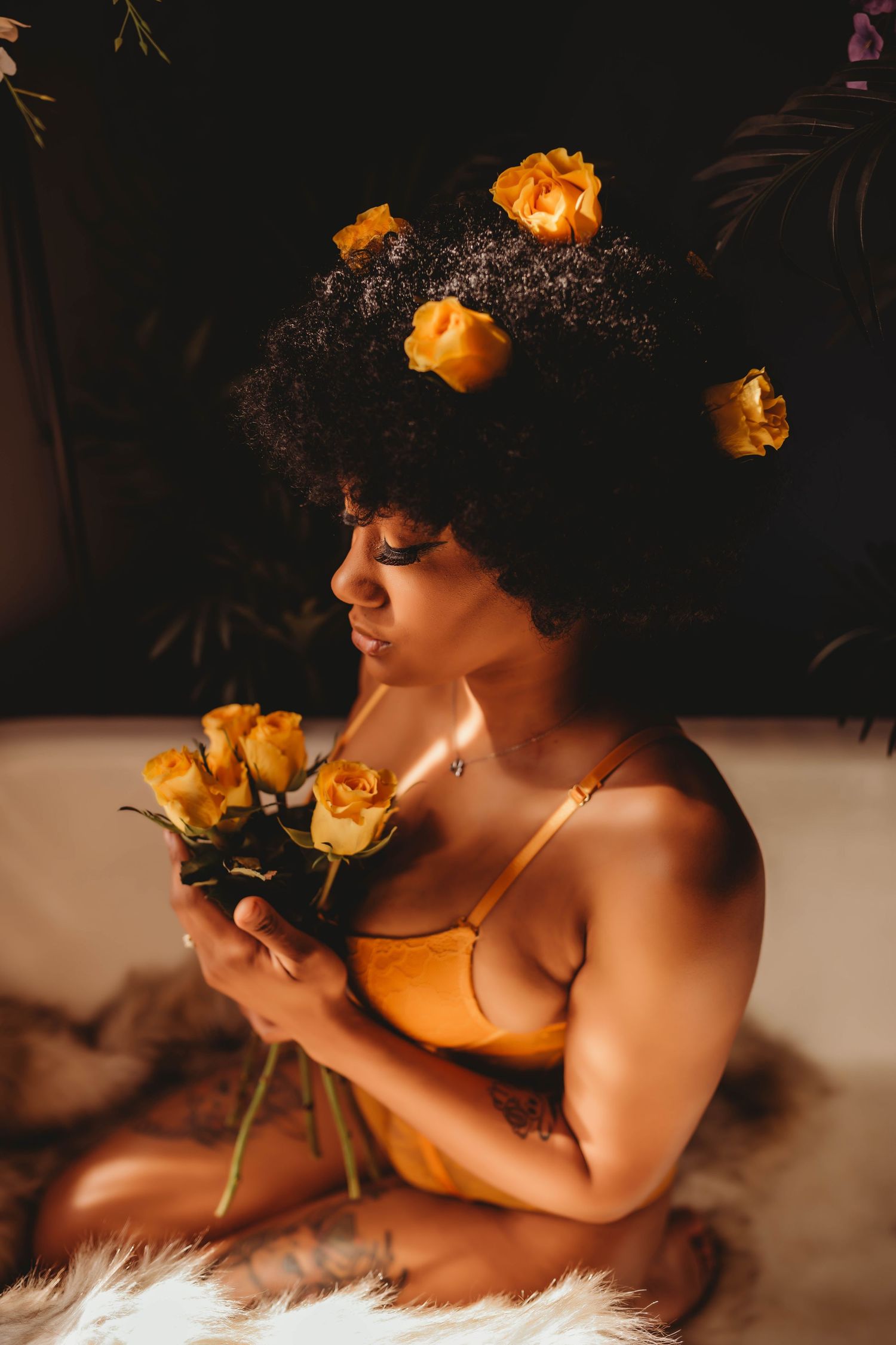 Artistic portrait with yellow roses against dark background creating contrast.