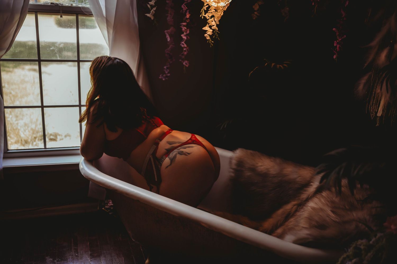Silhouetted figure against window light in atmospheric boudoir photography.