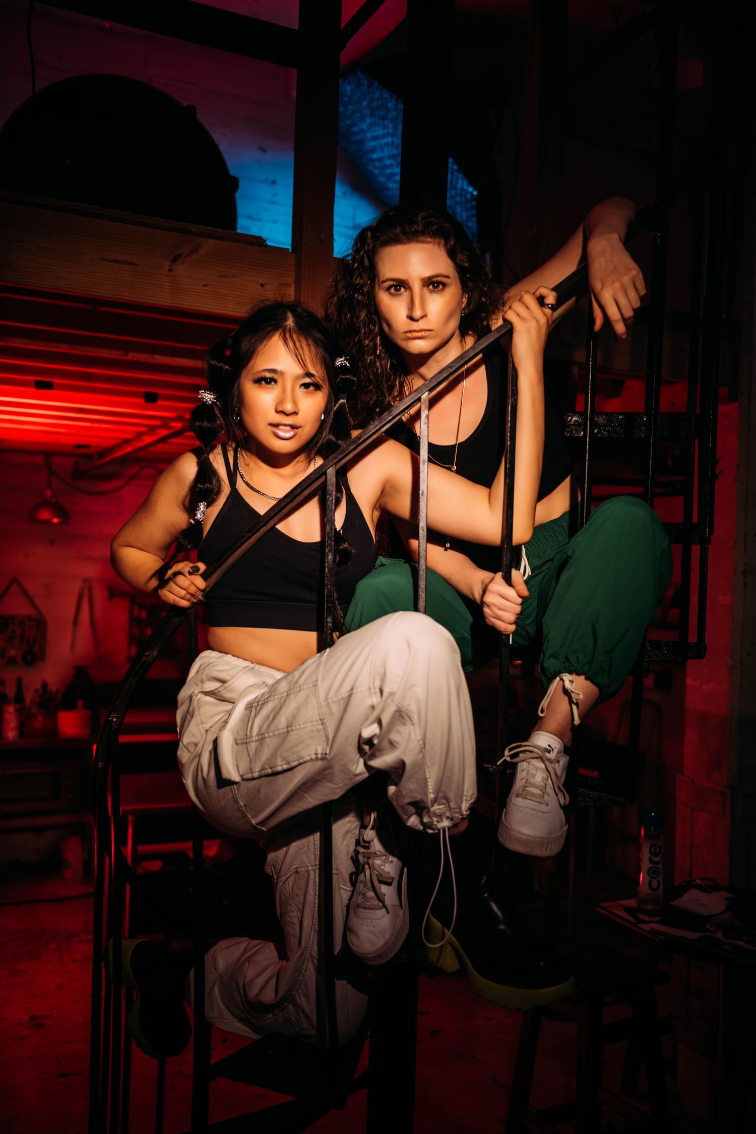 Dramatic red and black lighting in a dance studio with hanging poles and workout equipment.