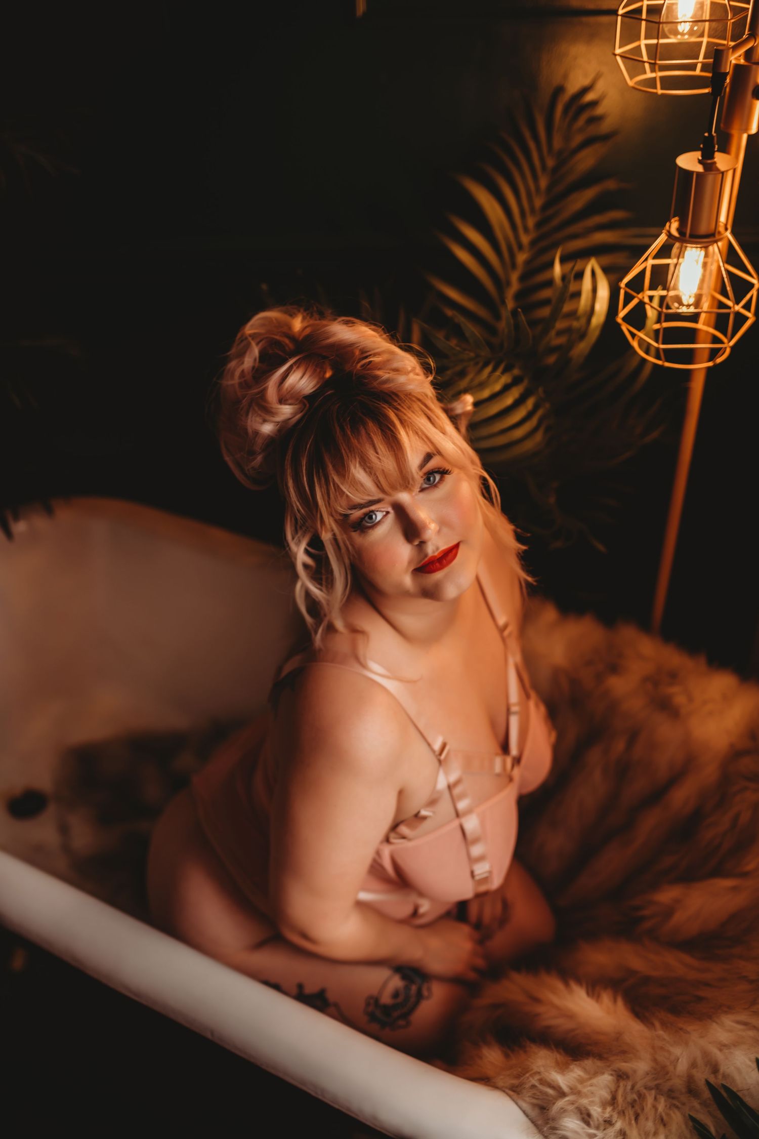 Moody boudoir photoshoot with warm lighting and palm leaf shadows creating an intimate atmosphere.
