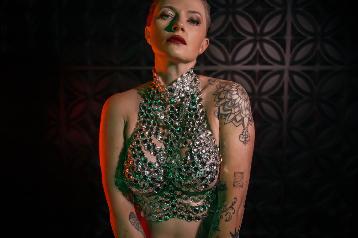Dramatic portrait with ornate crystal bodice against dark background.