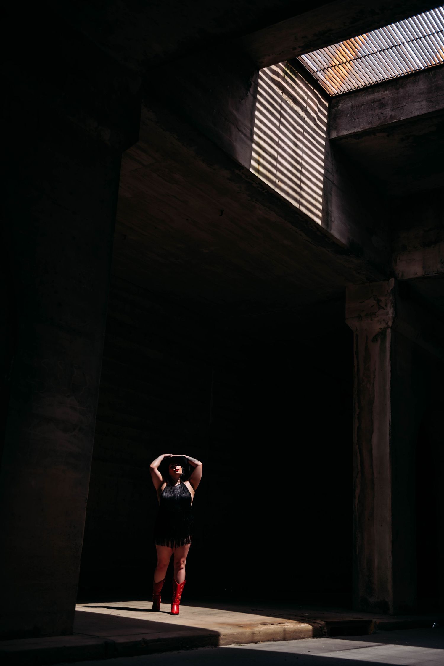 Dramatic silhouette of a dancer in a dark warehouse with beams of light streaming through.