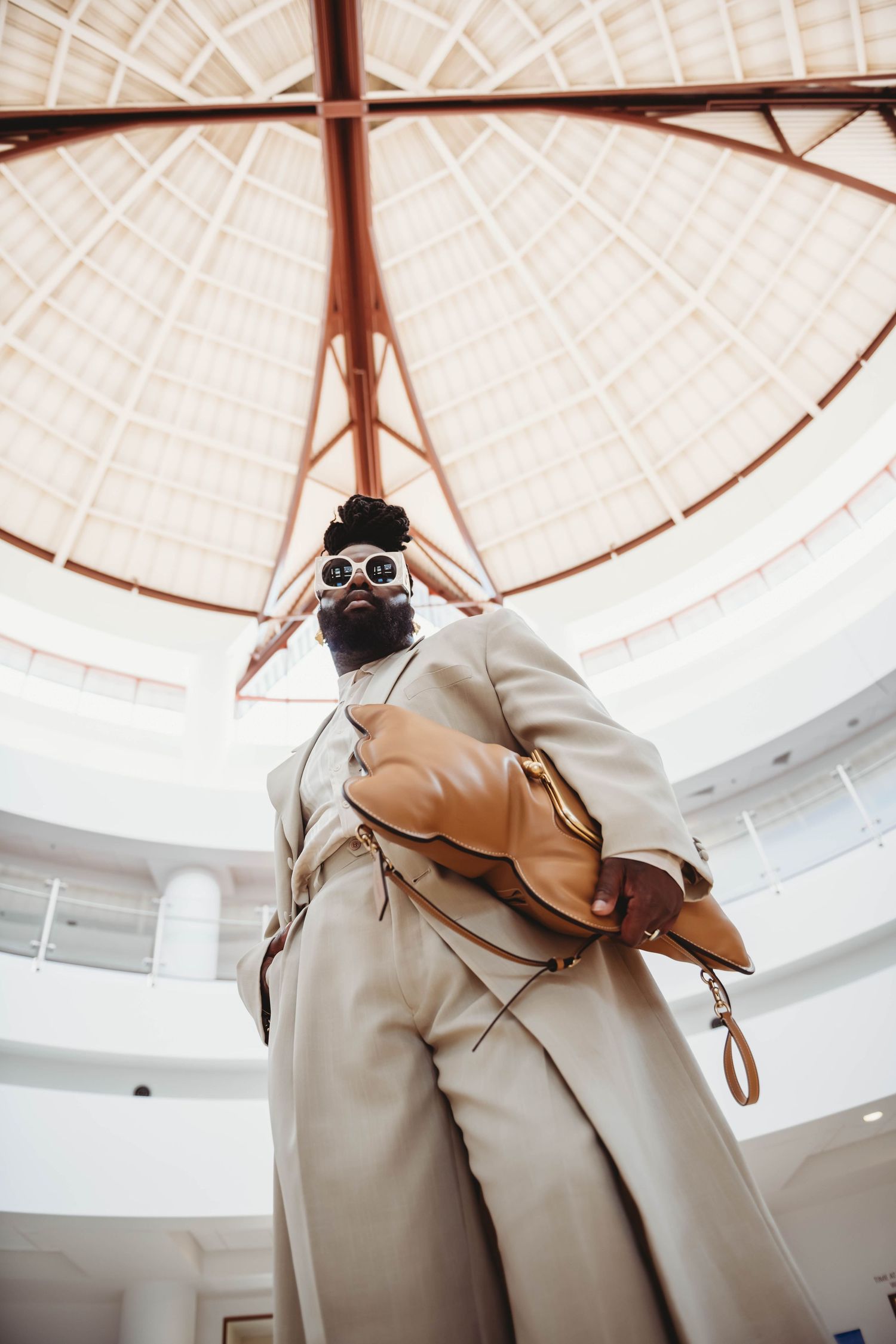 Modern architecture interior with geometric domed ceiling and figure in beige suit.