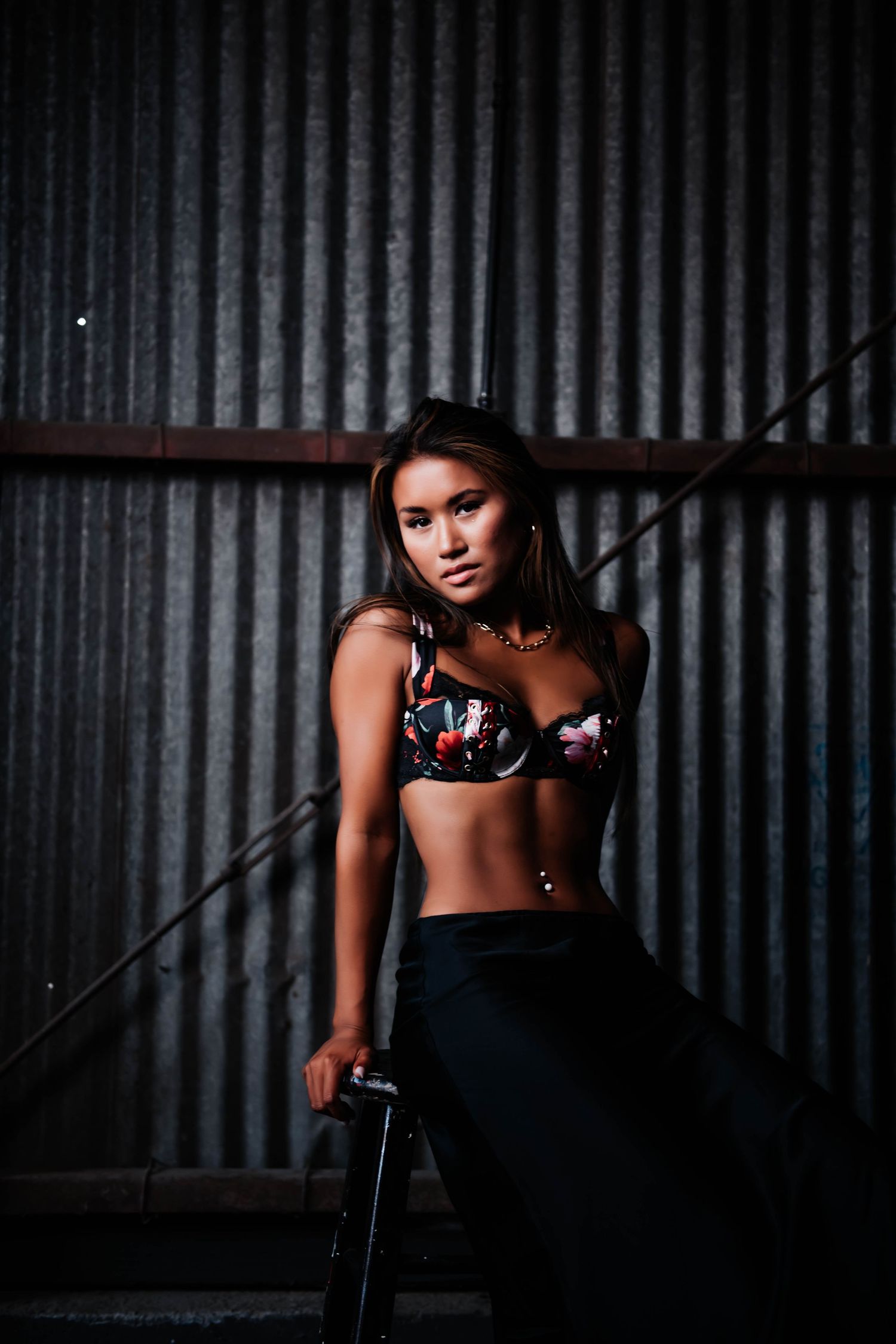 Moody fashion portrait against corrugated metal wall in urban setting.