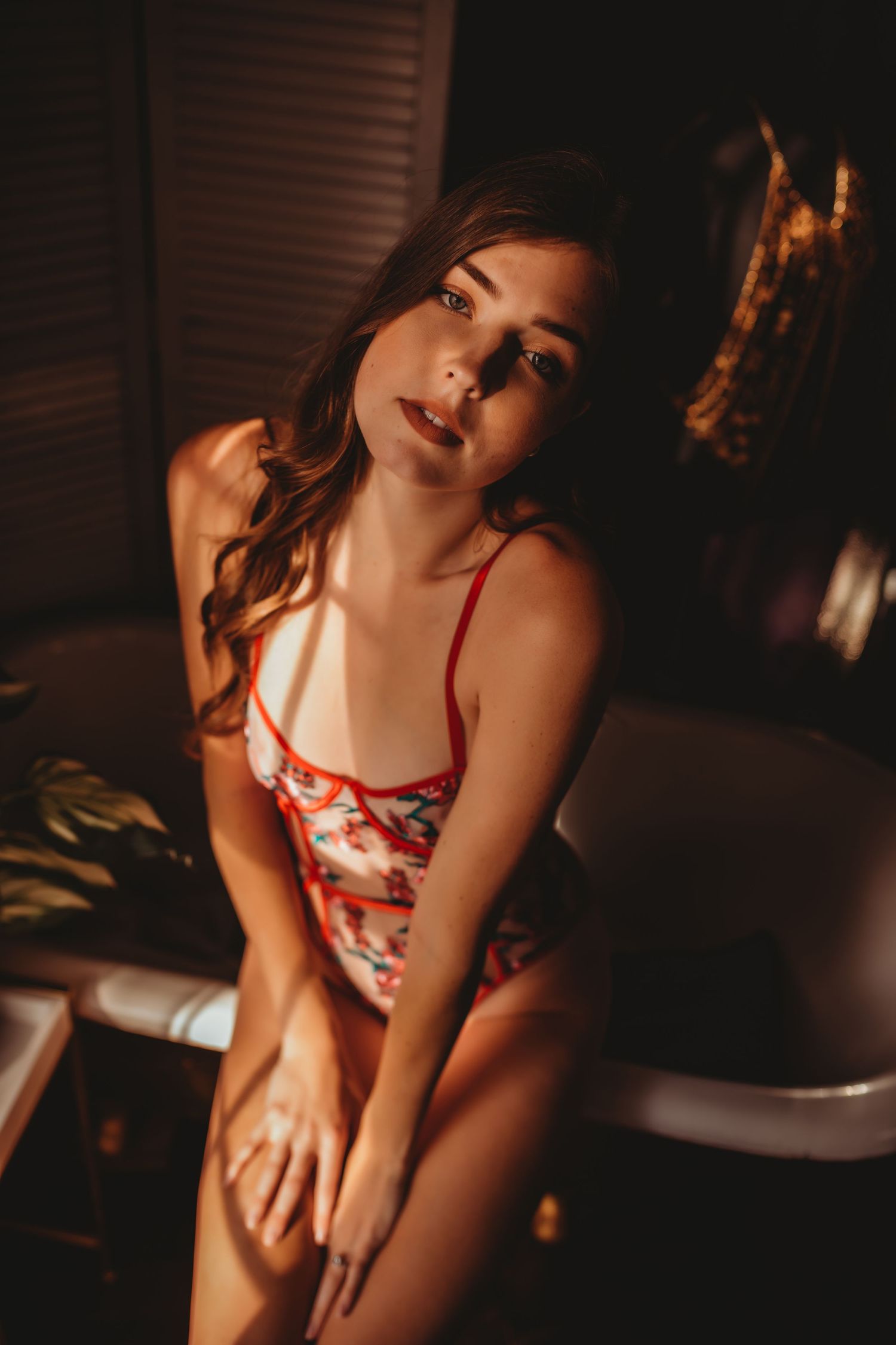 Intimate boudoir photography in red lingerie with moody lighting.