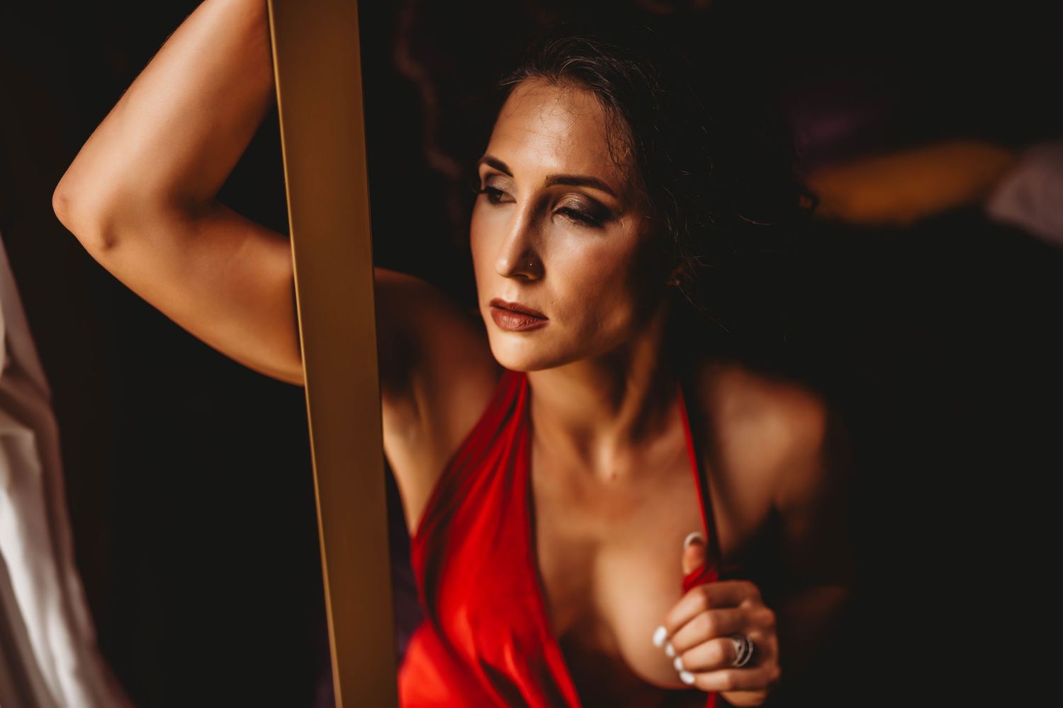 Dramatic boudoir photography with moody lighting and red accents creates an intimate atmosphere.