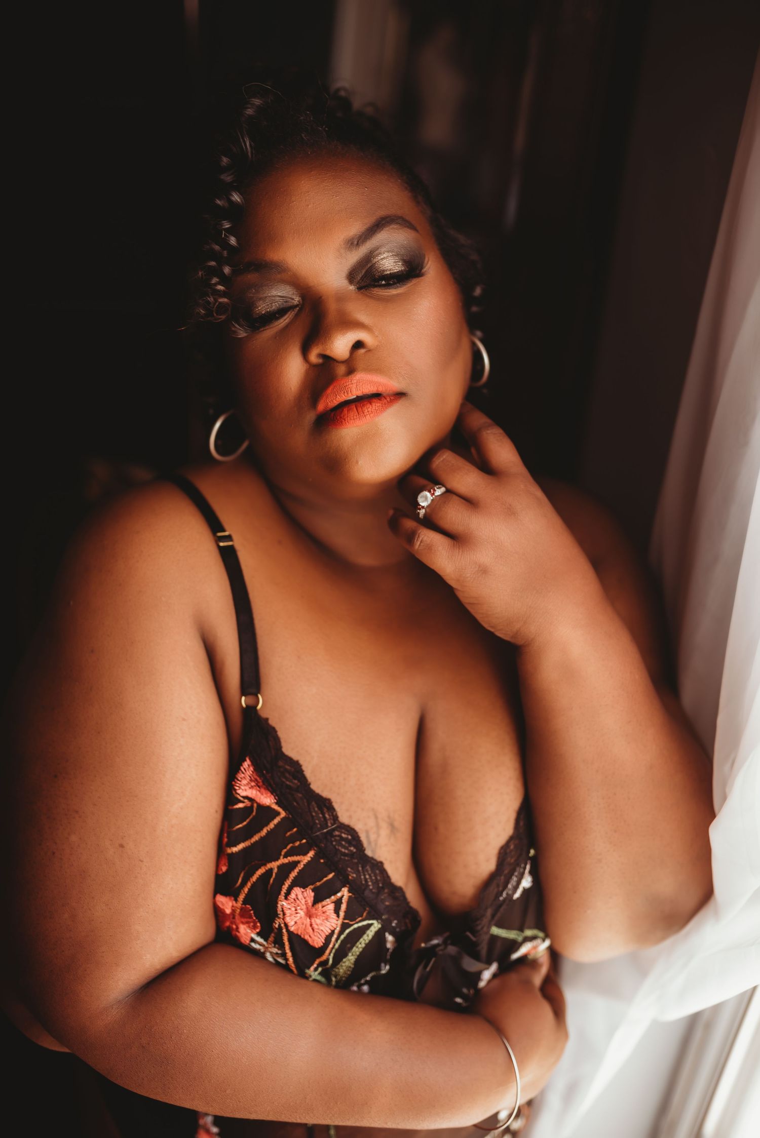 Sensual boudoir portrait in black lingerie with natural window light.