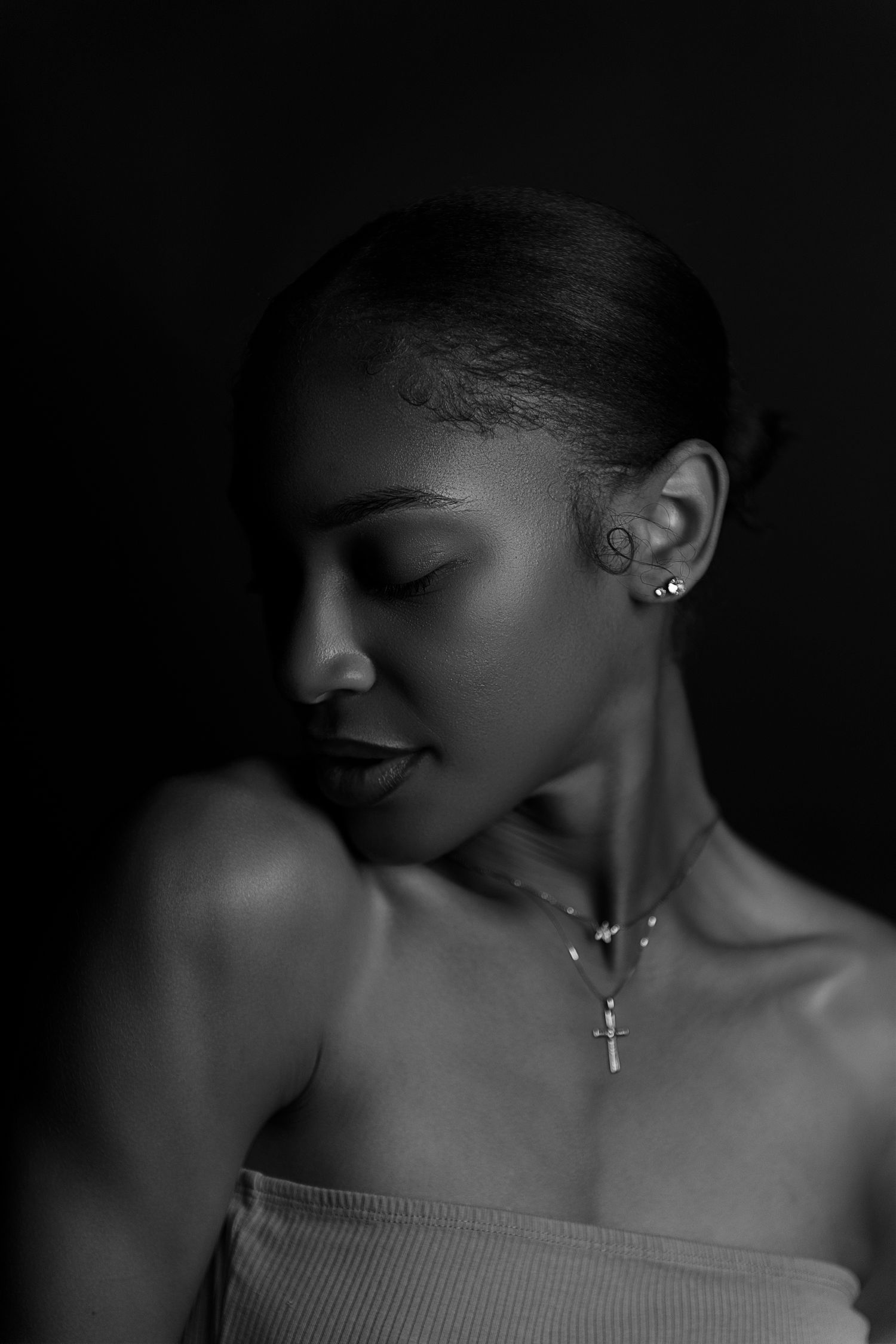 A dramatic black and white portrait series showing silhouettes and profiles against dark backgrounds with delicate jewelry.