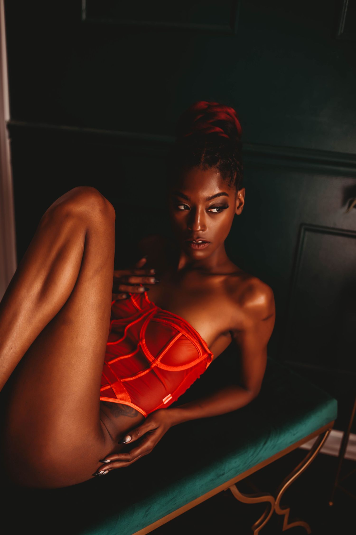 Artistic red lingerie photography with dramatic lighting and teal surface contrast.
