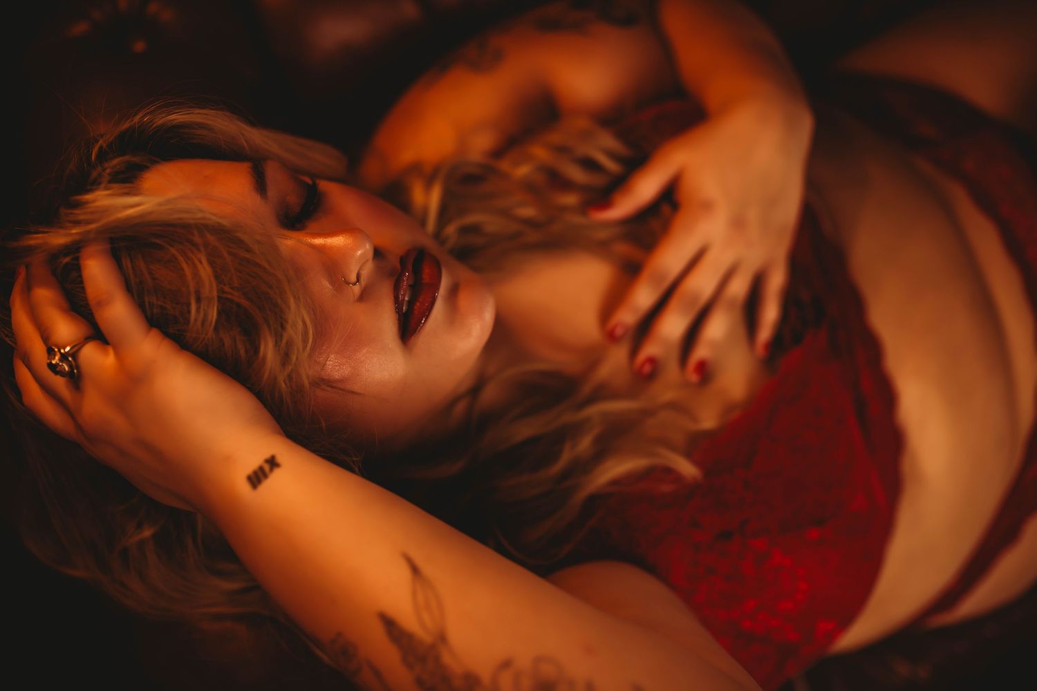 Intimate boudoir photo with red lingerie in warm lighting creating moody atmosphere.