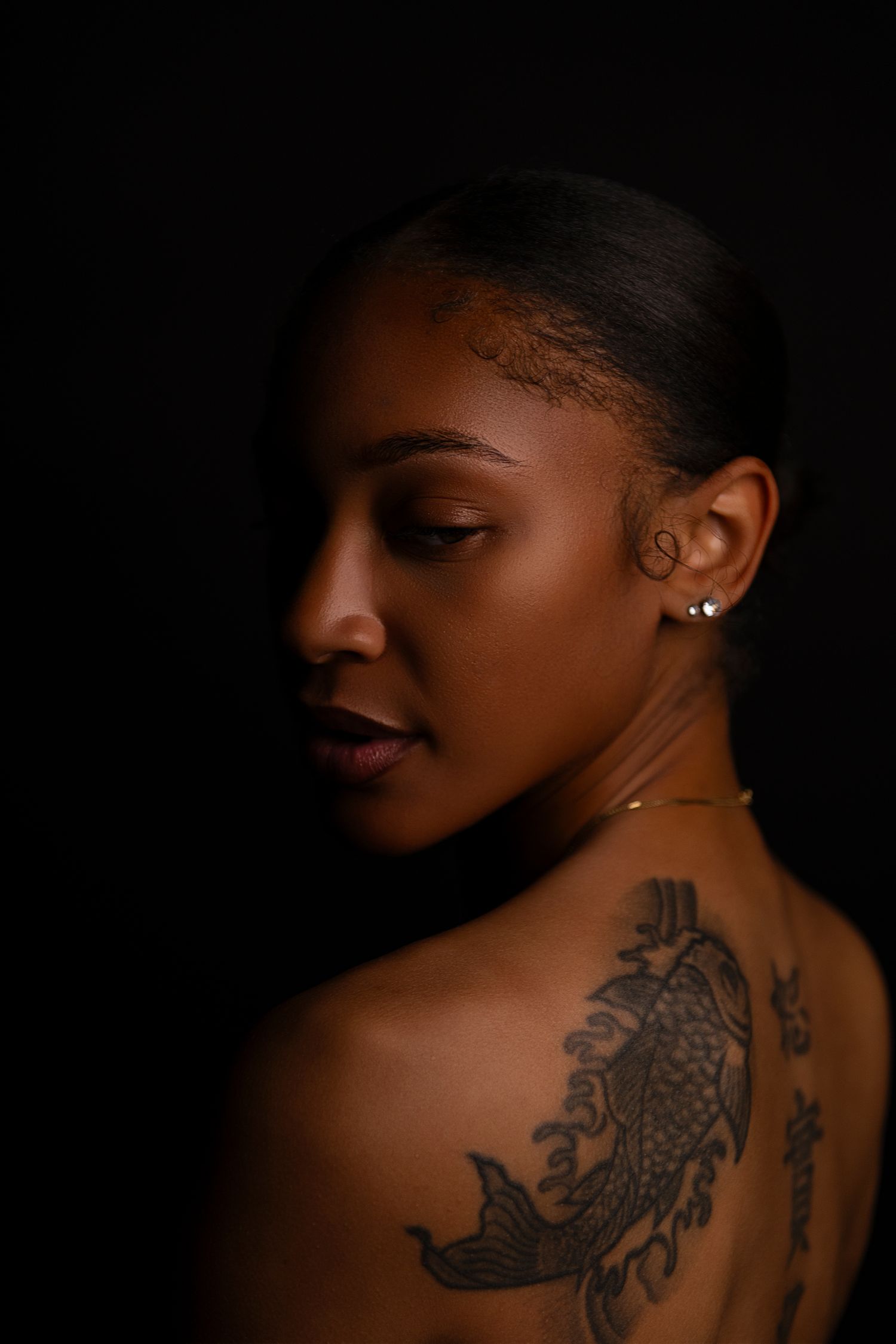 Artistic black and white photo series showing a dark tattoo on someone's back against a black background.