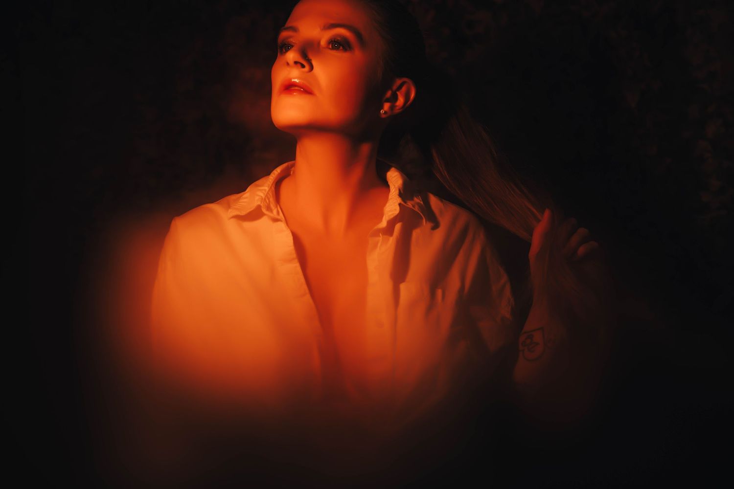 Dramatic boudoir portraits illuminated by warm orange lighting creating silhouettes.