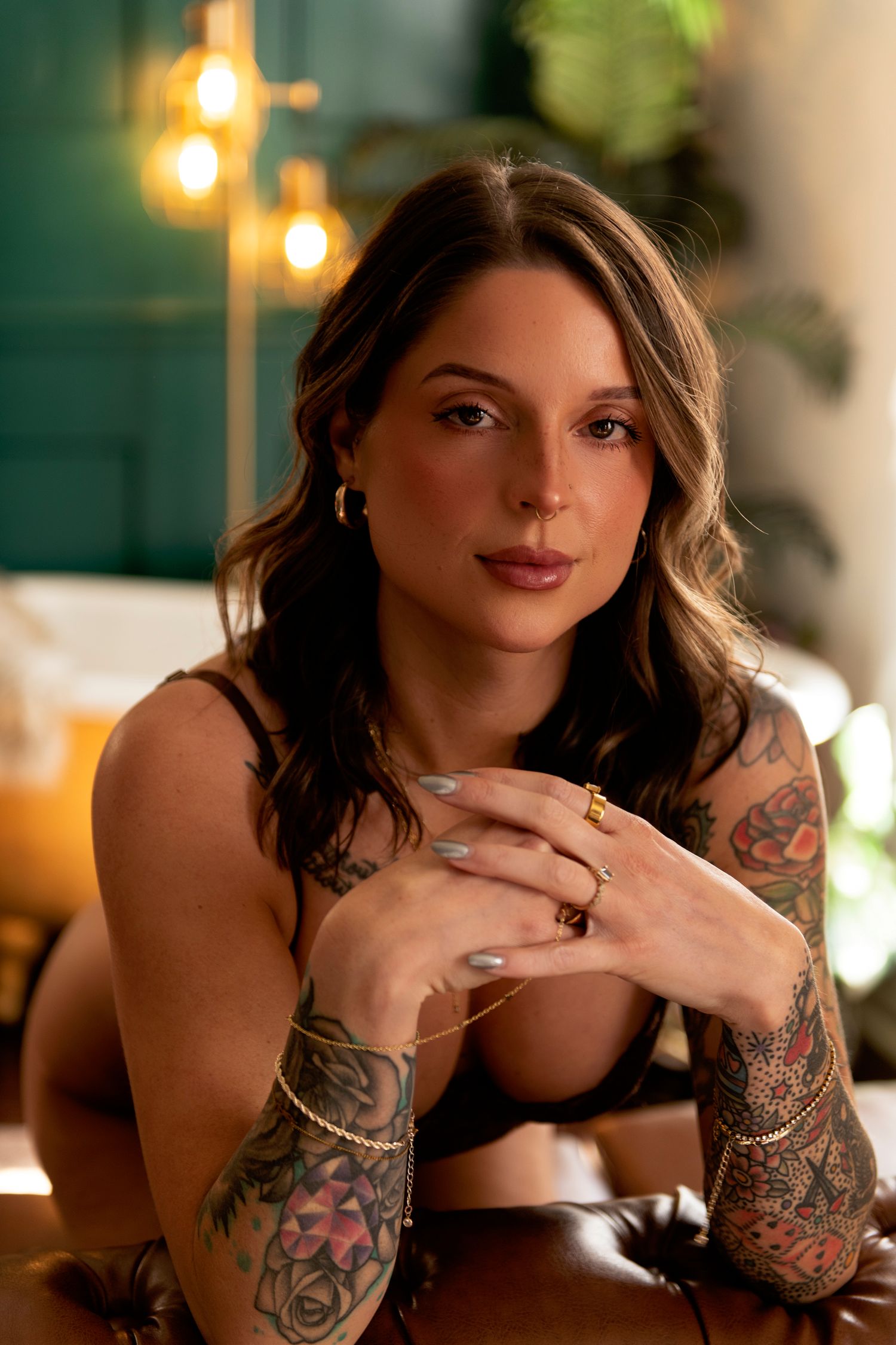 A series of five photos showing a person with tattoos and jewelry posing against a warmly lit background.