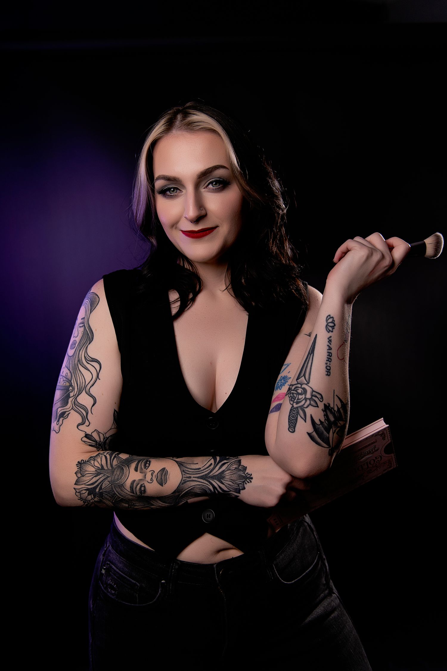 Dark and moody boudoir photoshoot featuring tattoo art and black clothing against a deep purple background.