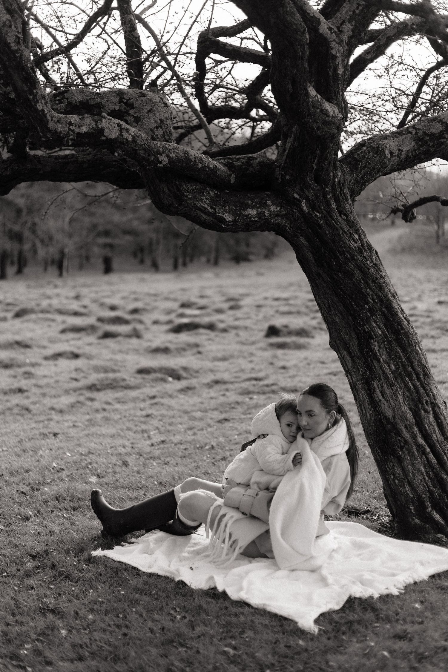 black and white photo of a mother and her 14 month old son cuddled up under a tree