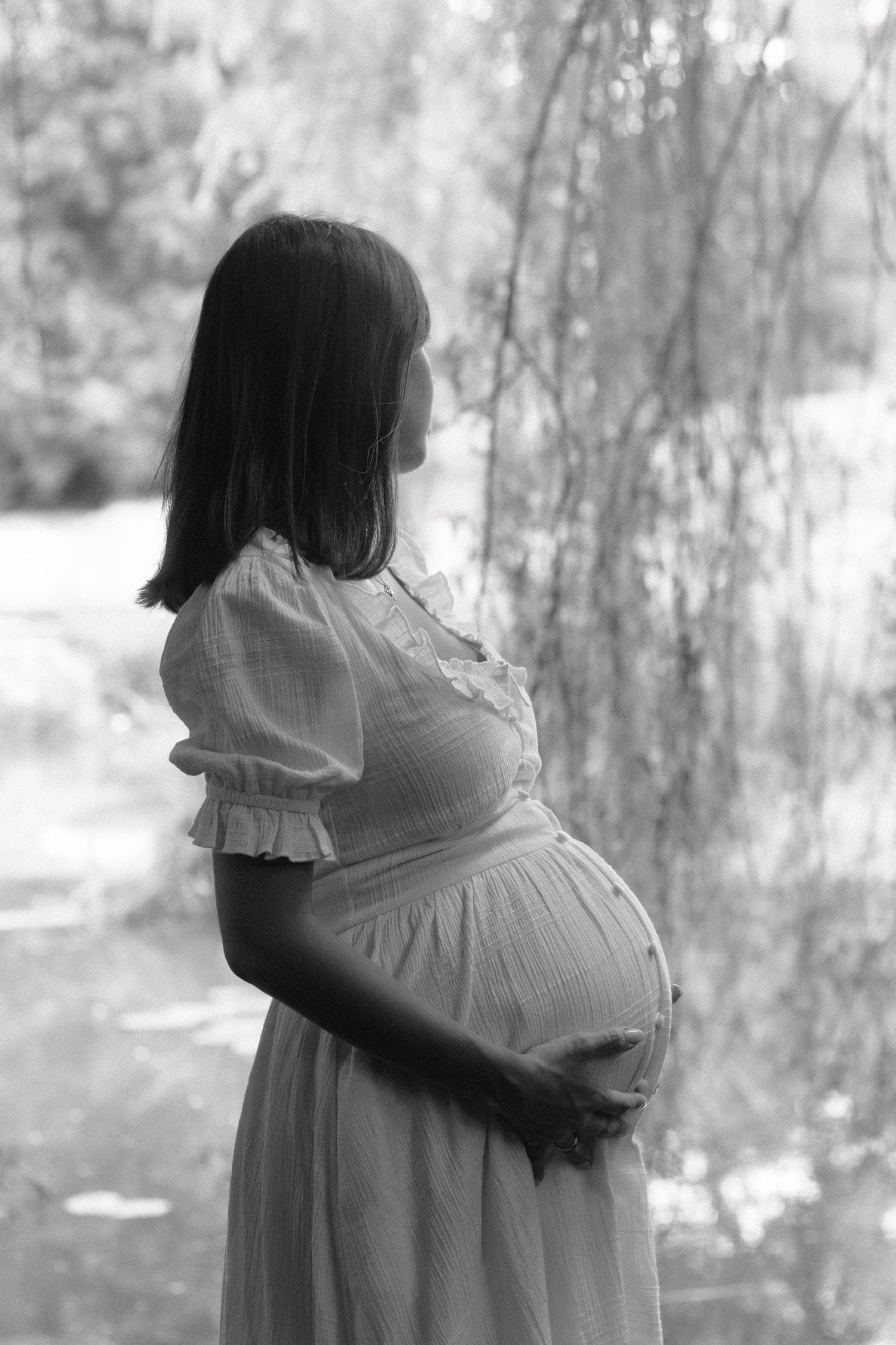 black and white photo of a woman holding her pregnant belly