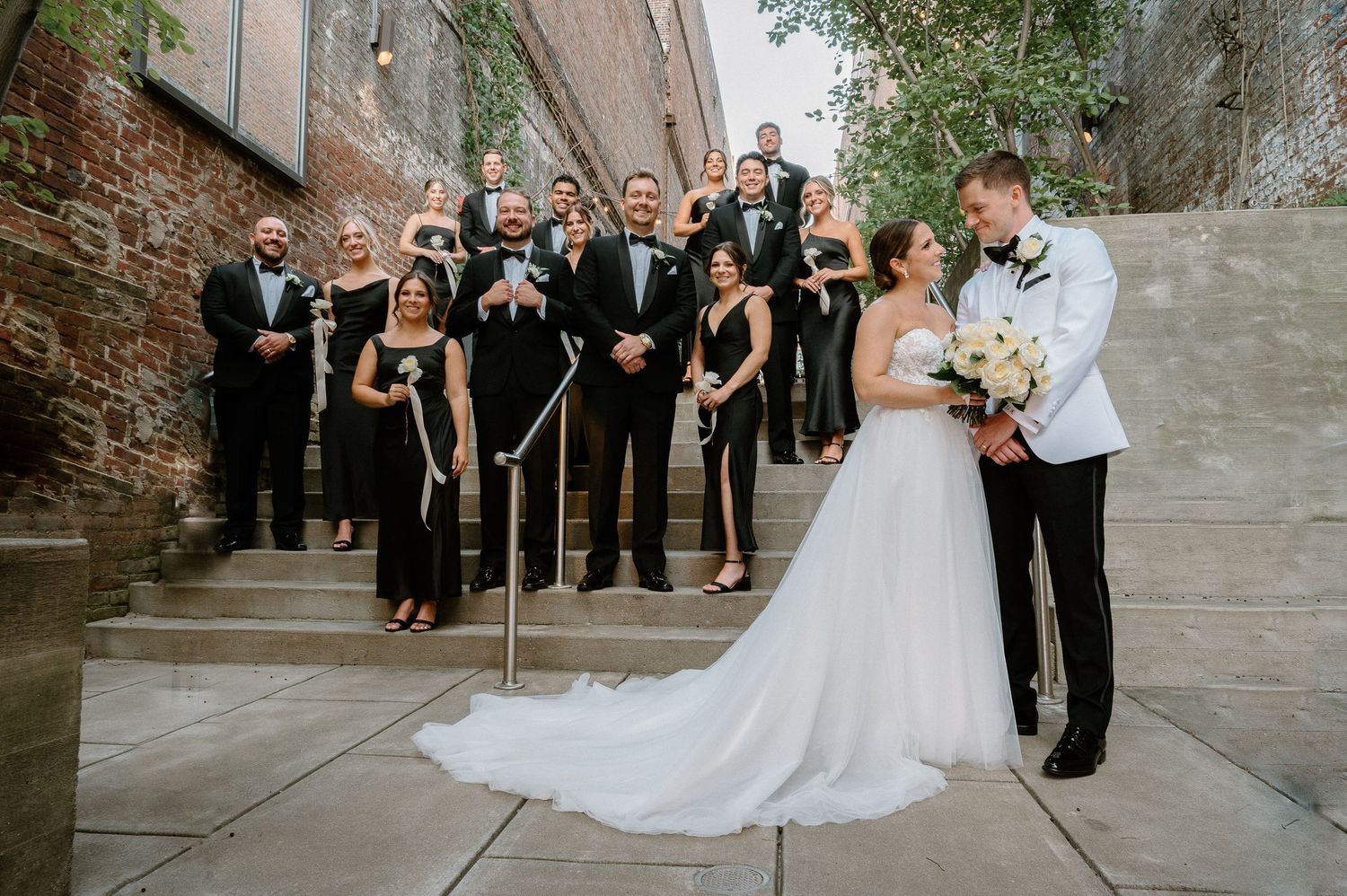 Wedding procession on outdoor walkway with vintage brick wall backdrop.