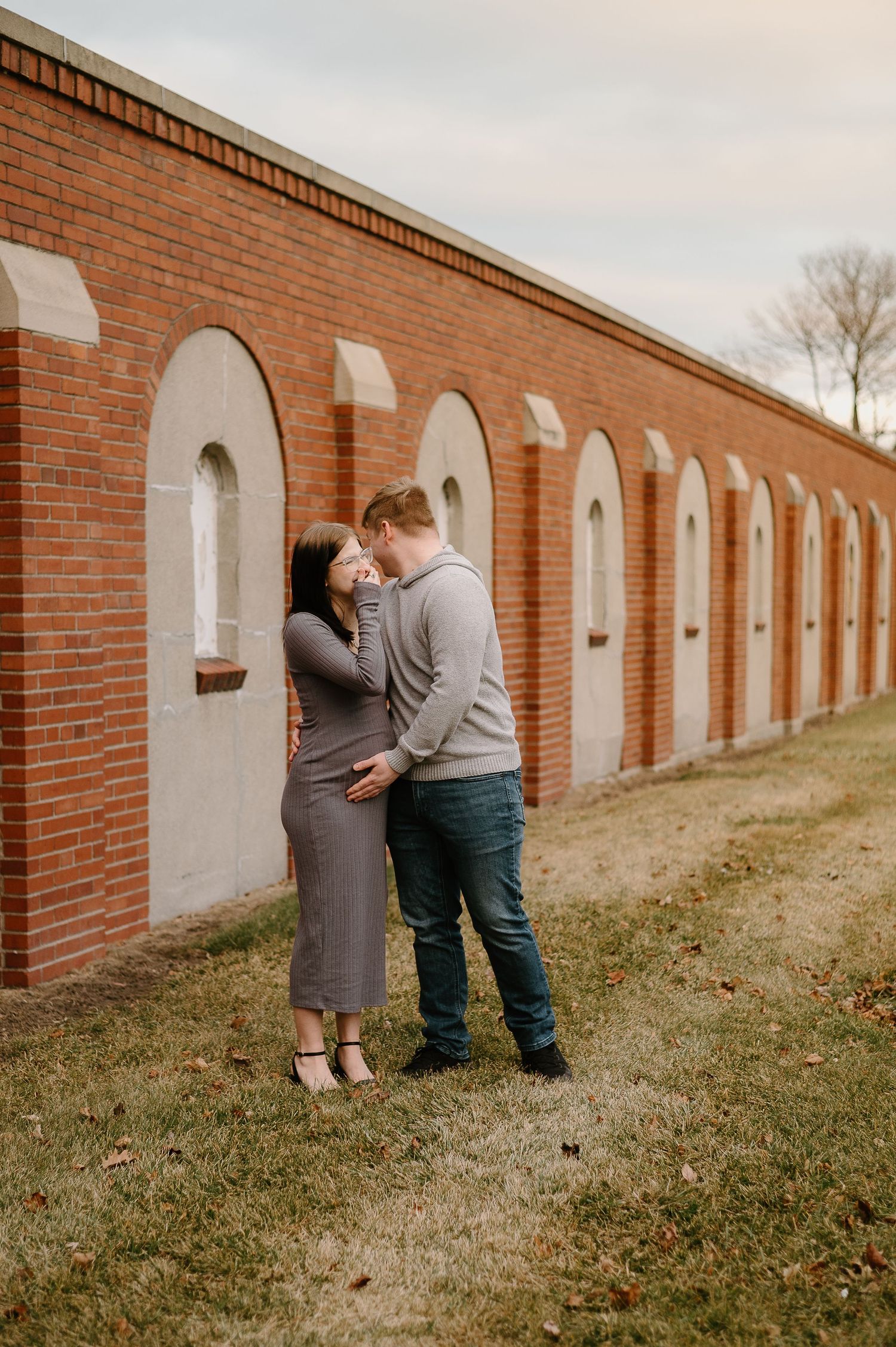 Romantic couple photo session along brick wall with arched windows.