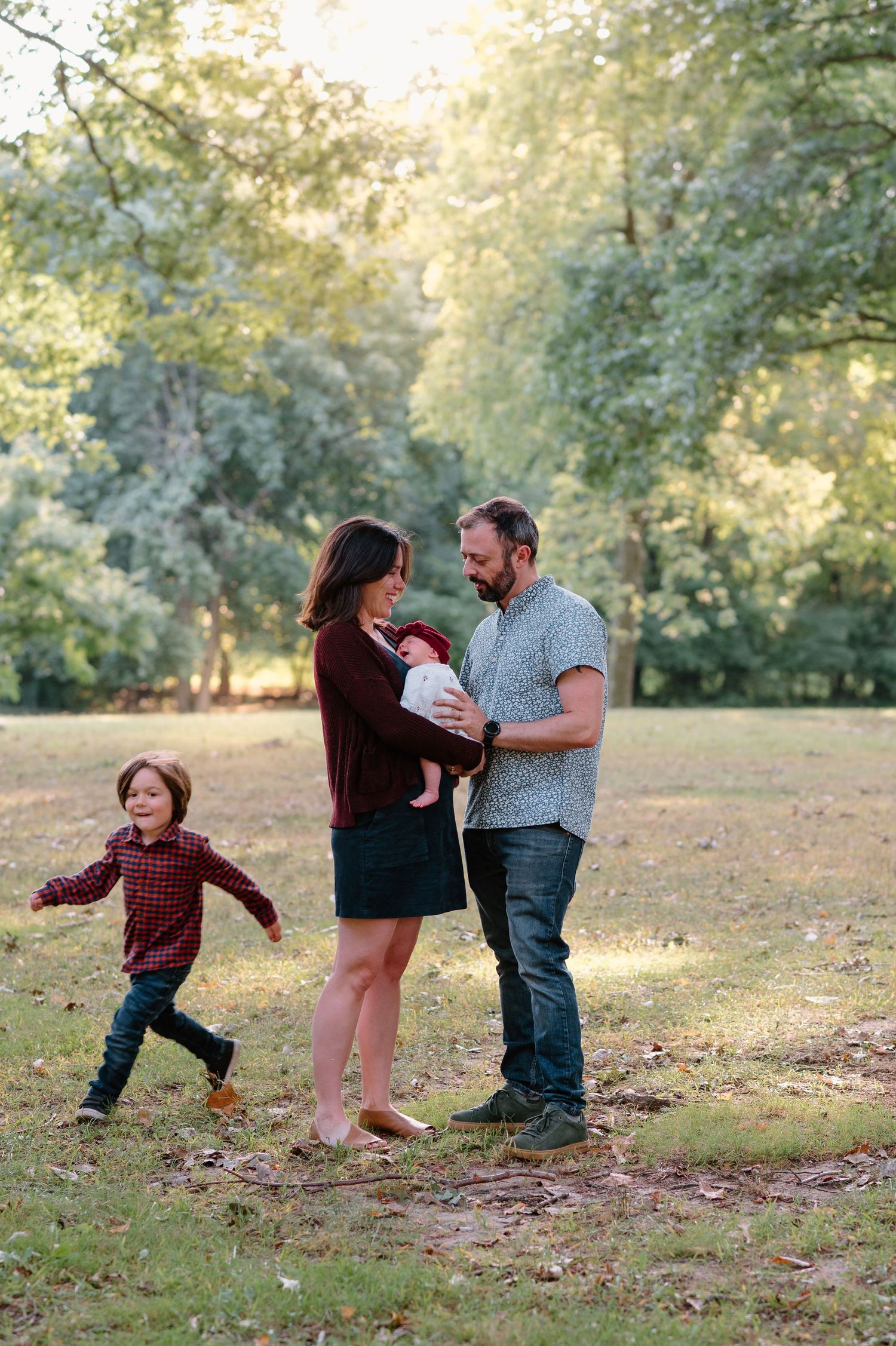 Family enjoys a candid moment together in a sunlit park setting.