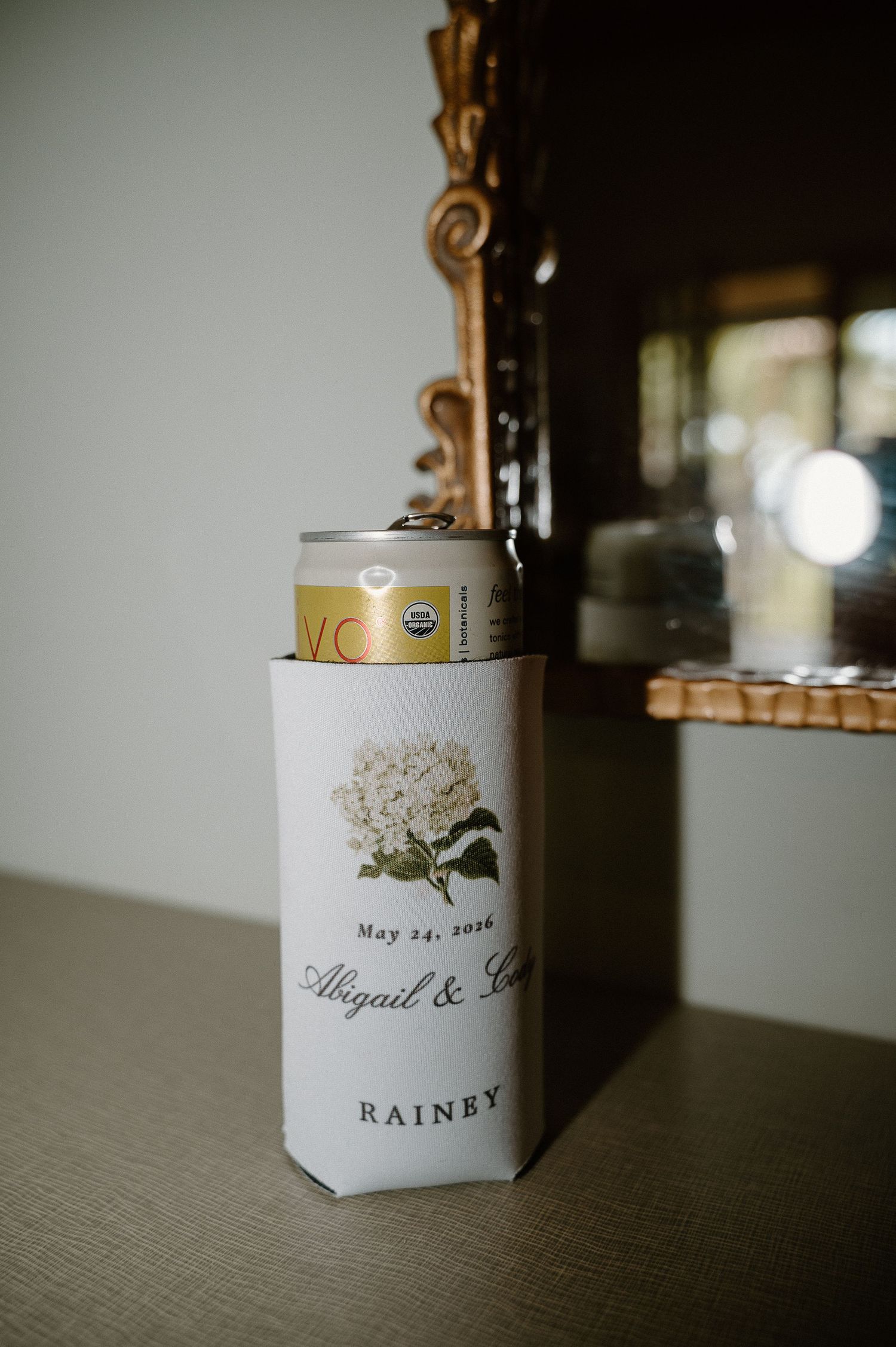 Custom wedding koozie for Abigail and Cole Rainey dated May 14, 2026, featuring a white hydrangea design.