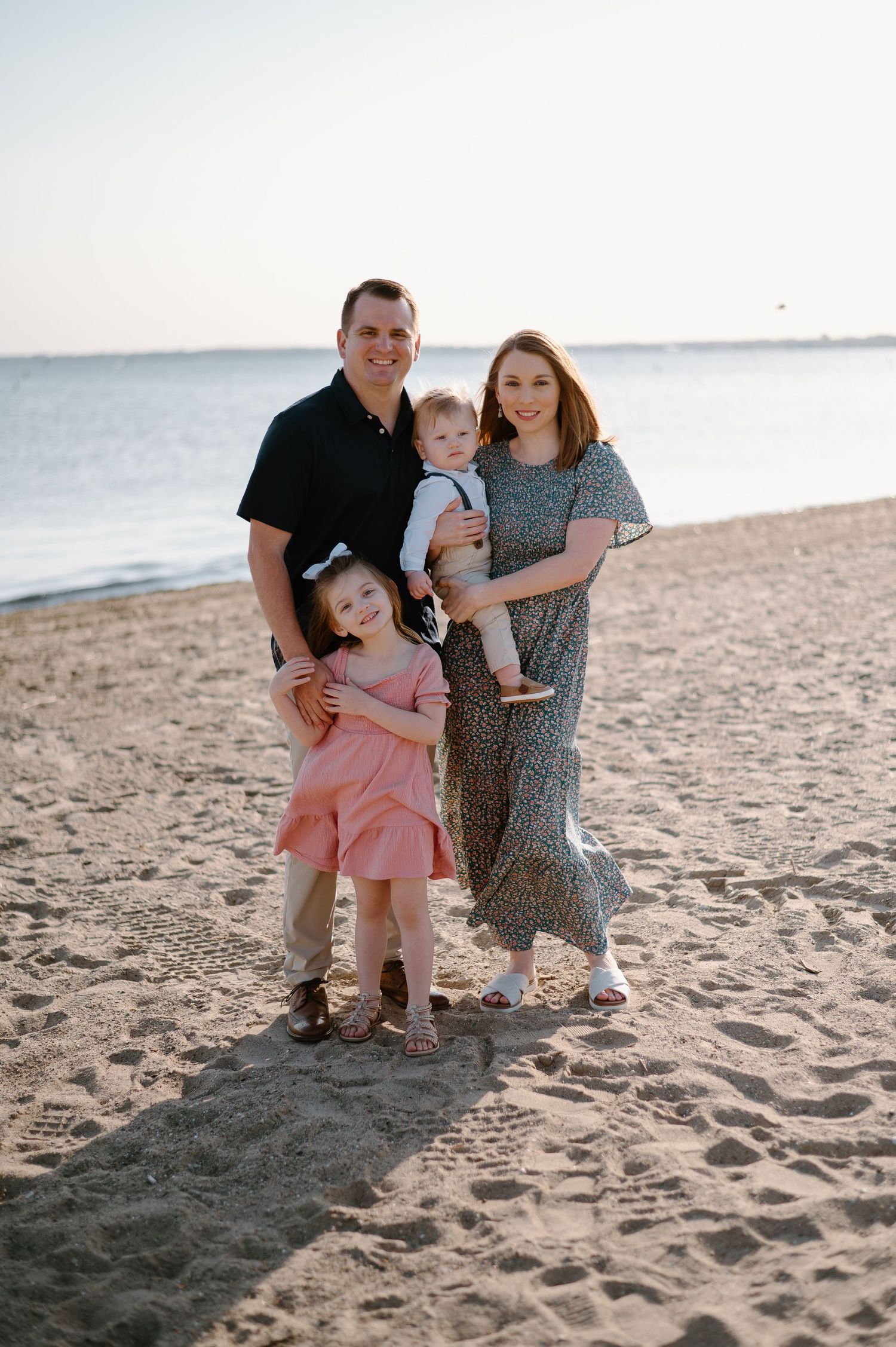 Family enjoying a sunset moment together on a sandy beach.