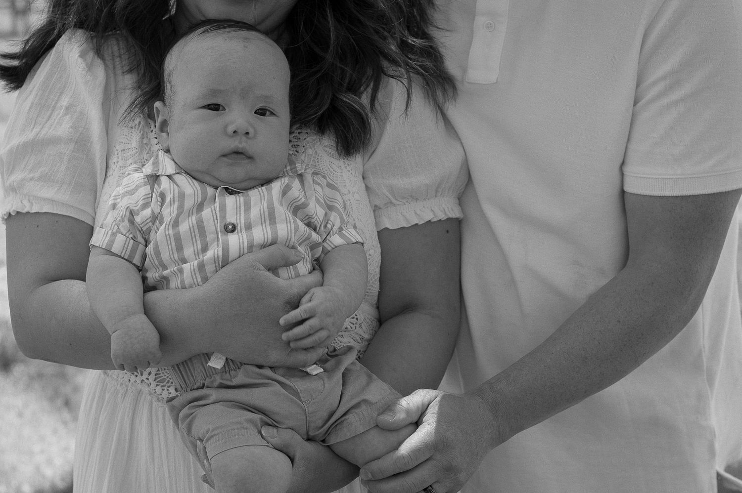 Sweet candid moments of a baby being held during family photo session.