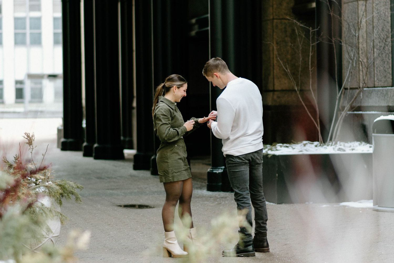 People walking through an urban space with dark pillars and white walls.