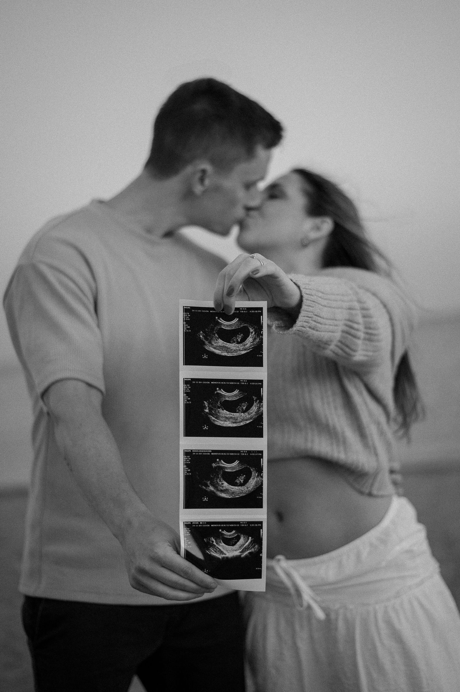 Series of intimate pregnancy announcement photos showing ultrasound images and embracing couple in black and white.