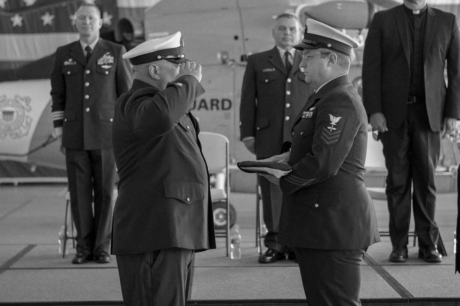 Military personnel in dress uniforms participate in a formal ceremony indoors.