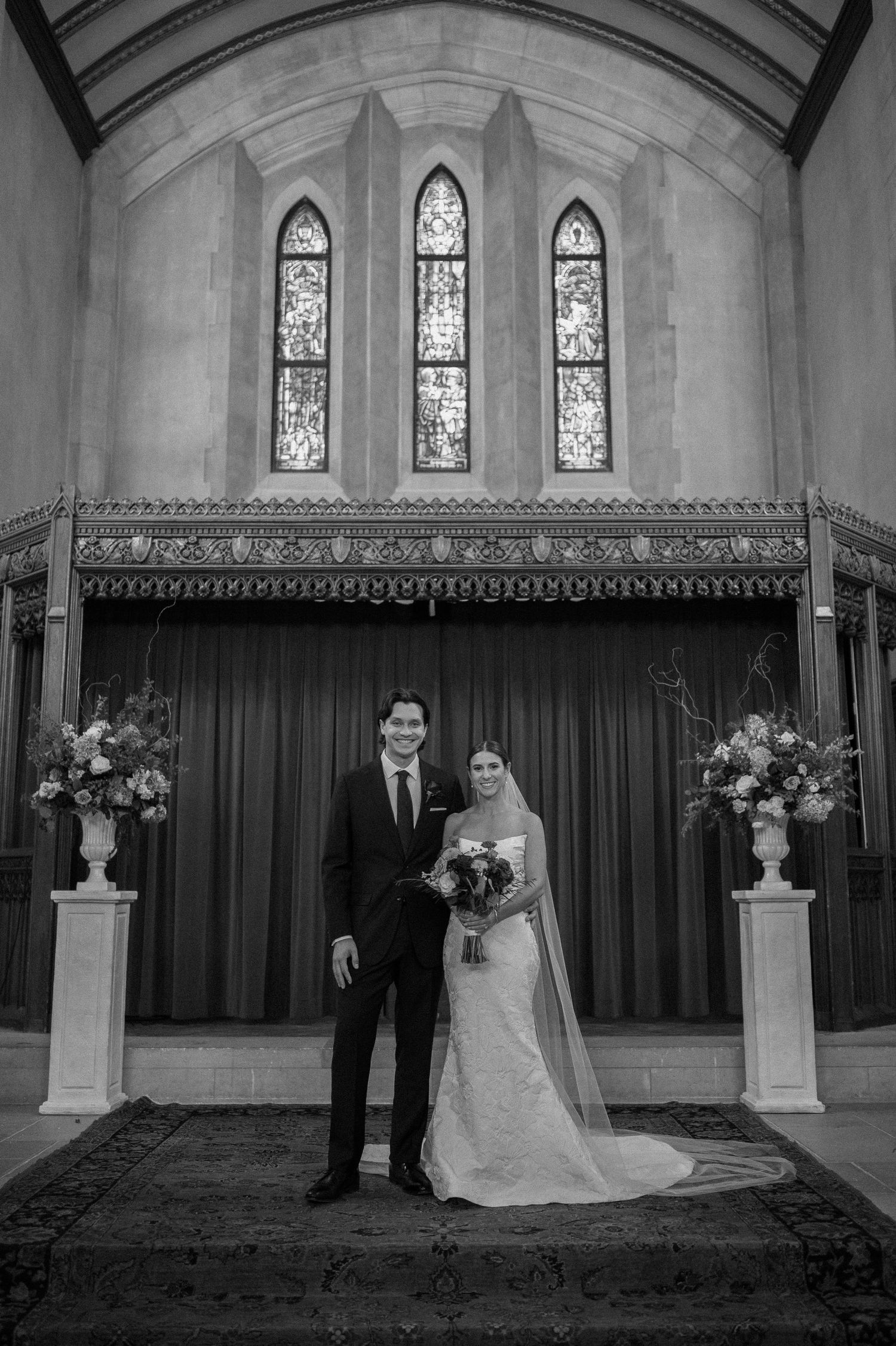 A black and white photo series showing a couple in formal wedding attire posing in a church with stained glass windows.