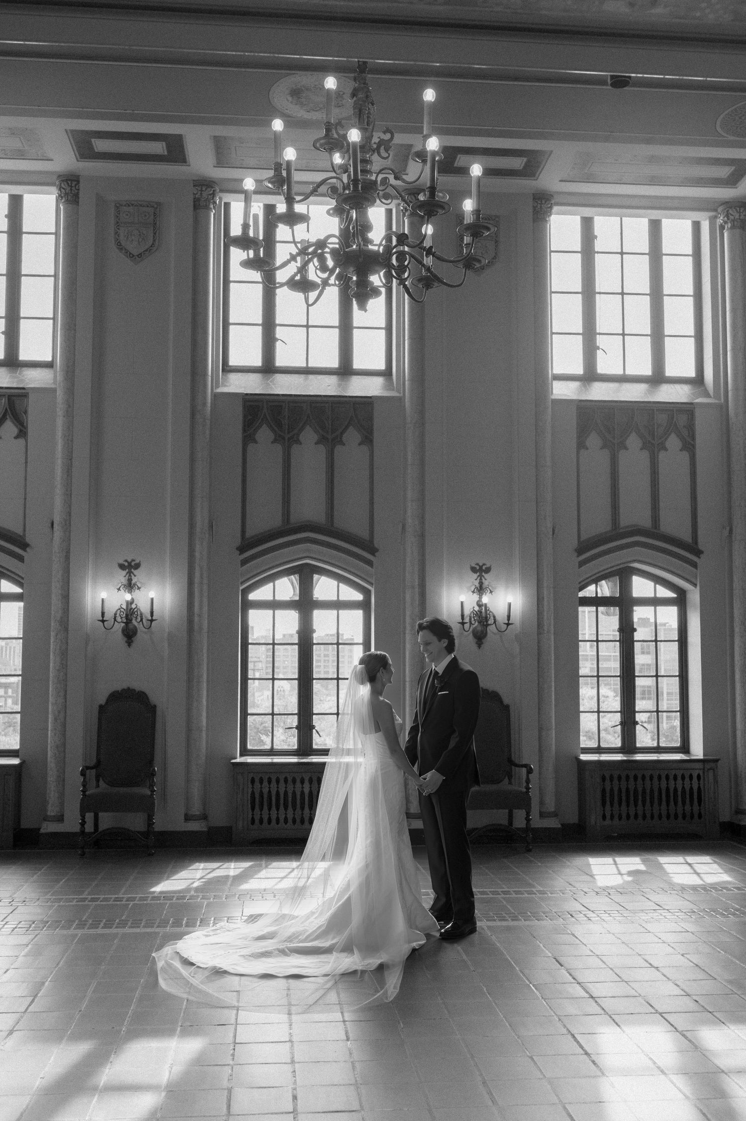 A series of black and white wedding photos showing a couple in an elegant hall with arched windows and natural light.