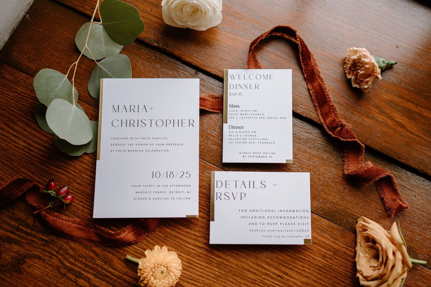 Wedding invitation suite with floral elements and eucalyptus leaves arranged on a rustic wooden table.