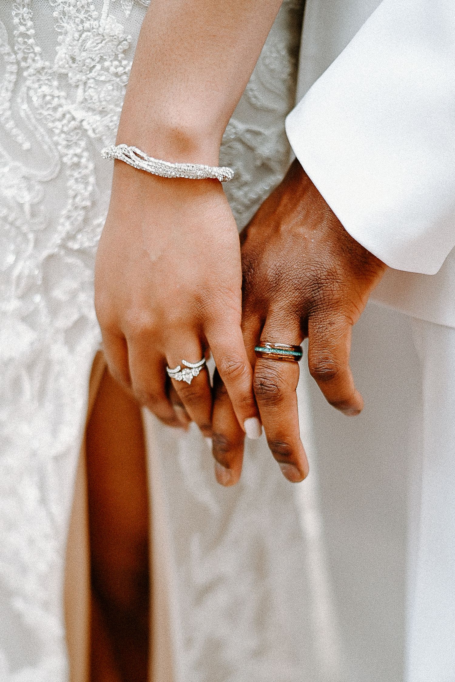 Close-up of wedding rings and joined hands showing the newly married couple's jewelry.