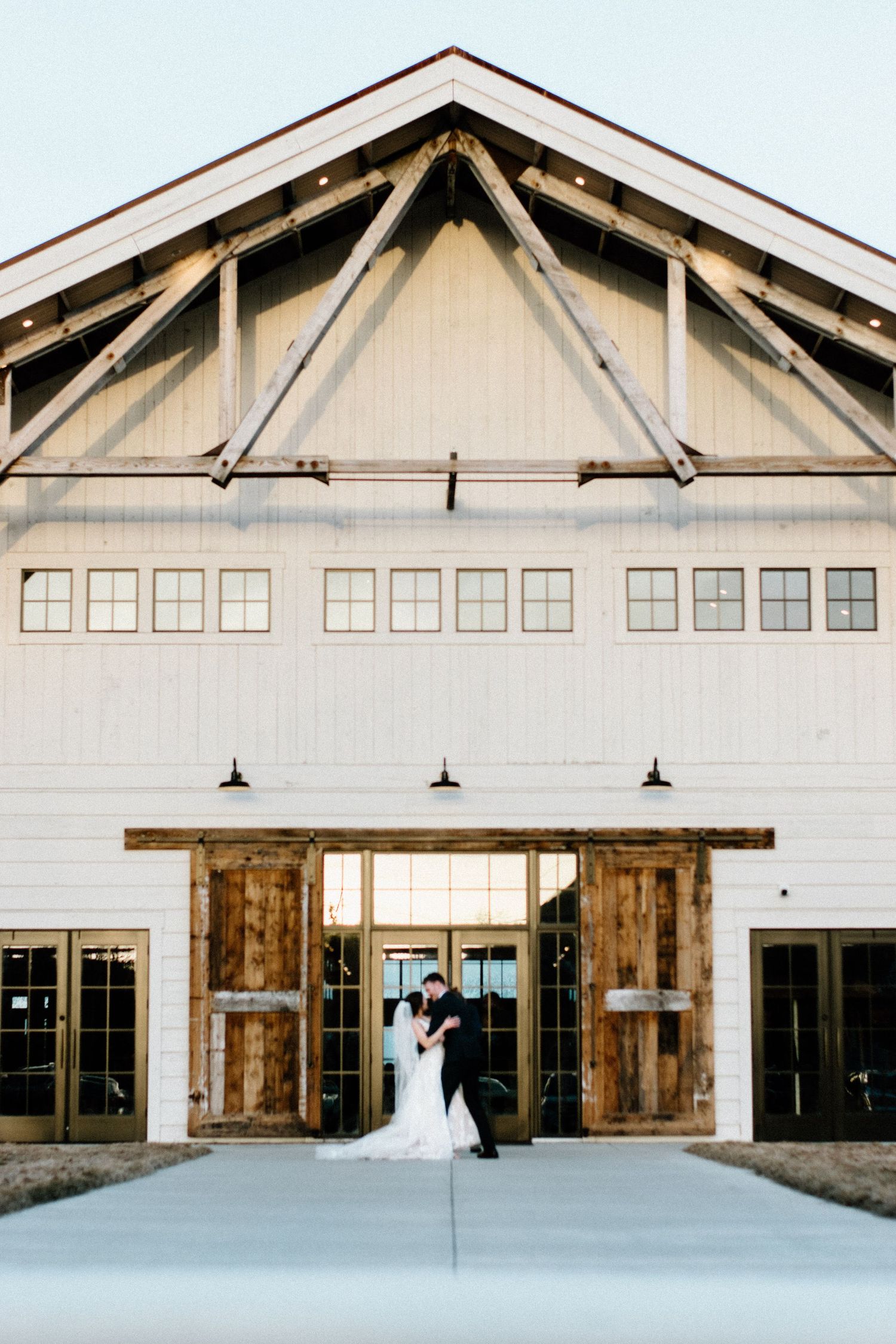 Modern white barn-style wedding venue with rustic wooden accents and large windows.