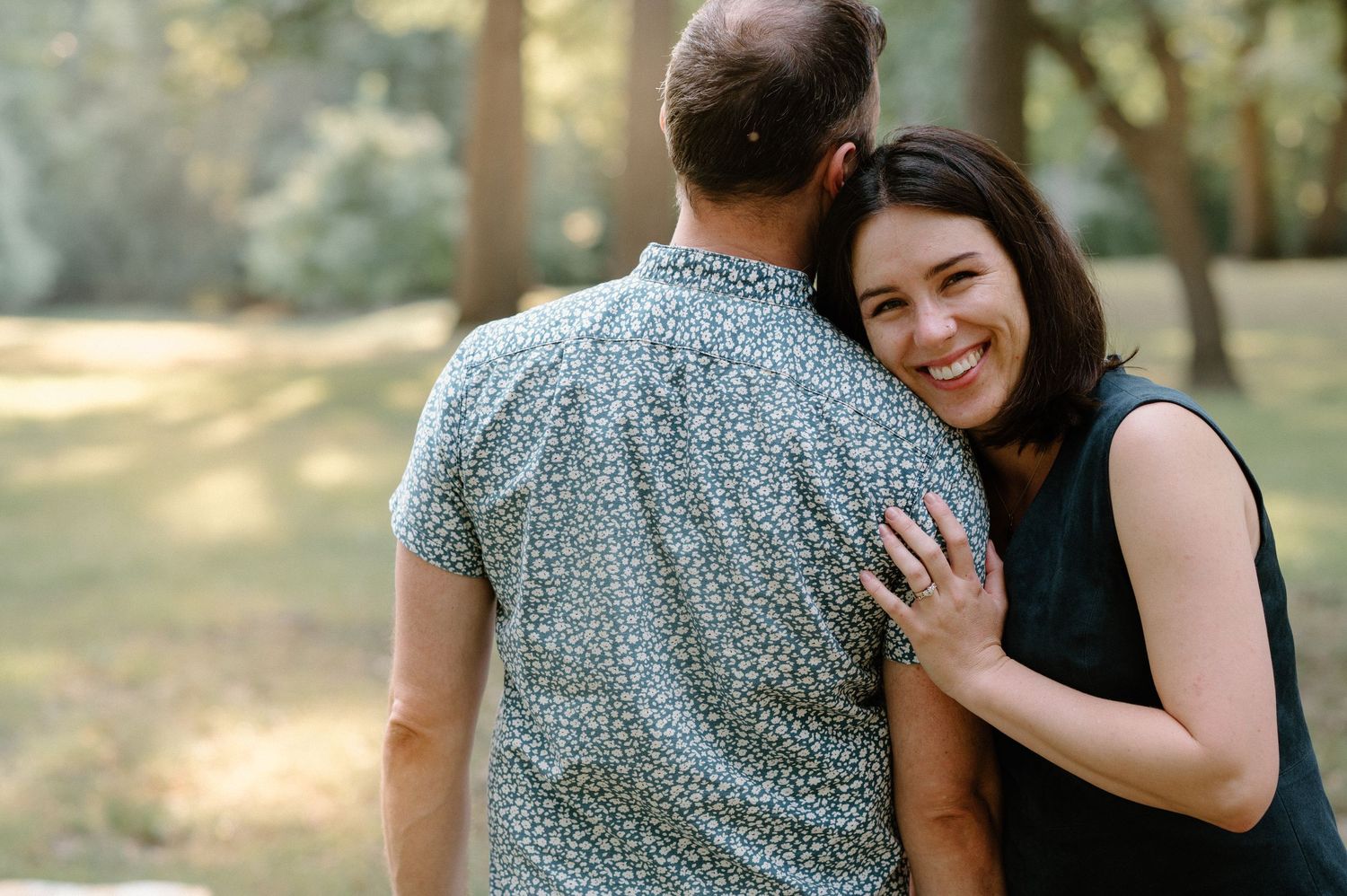 Two people share a warm embrace outdoors in a natural setting.