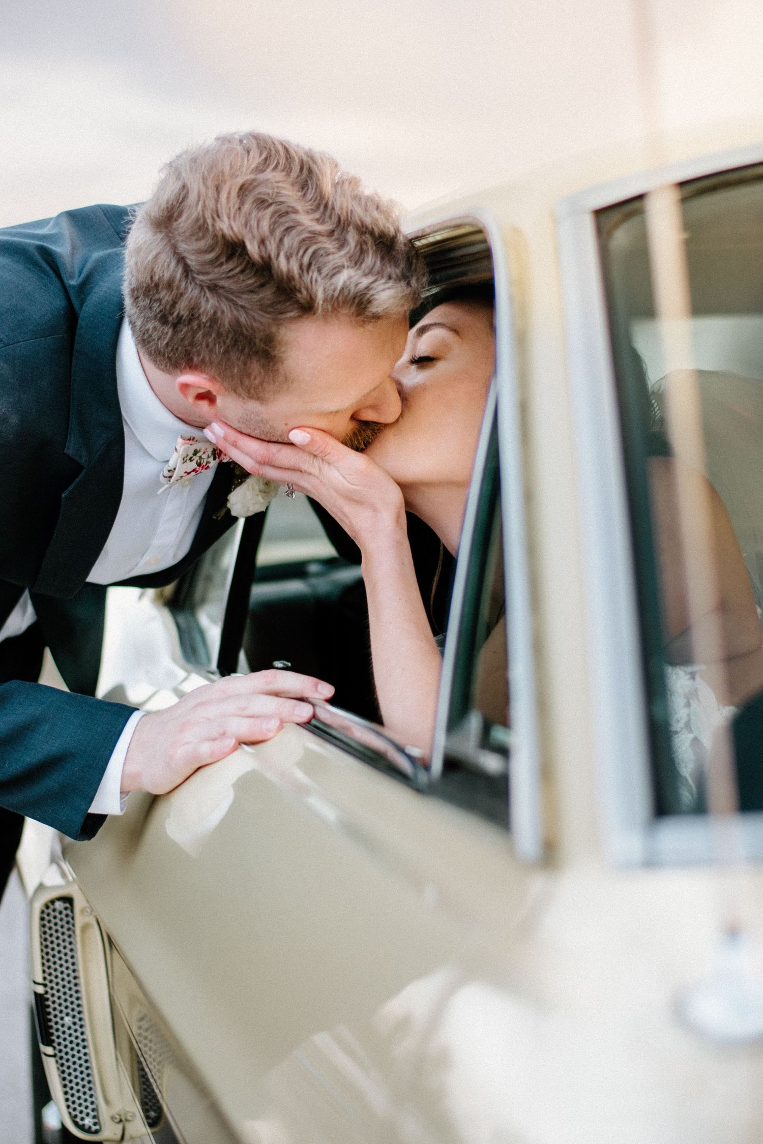 Intimate wedding car moment captured through window reflections.