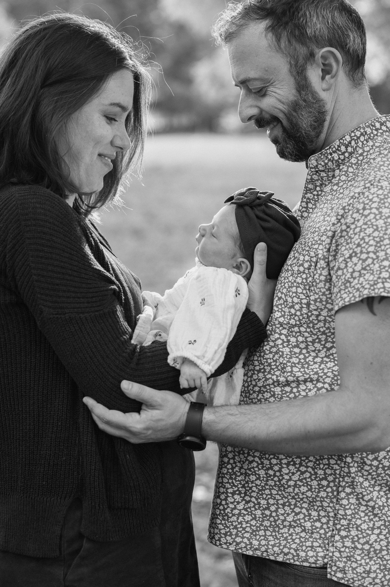 A black and white portrait of a family sharing a tender moment with their newborn.