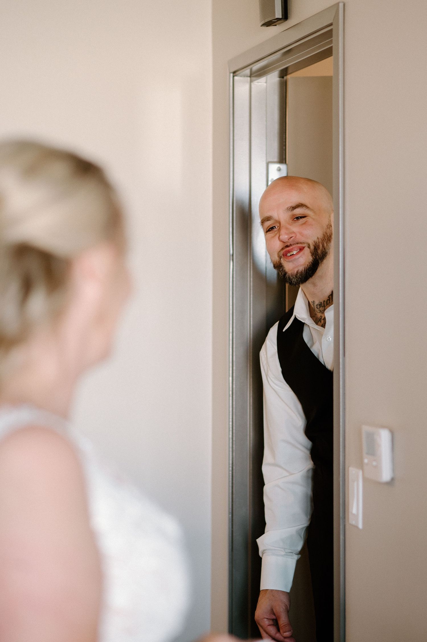 Candid first look moment captured through doorway during wedding preparations.