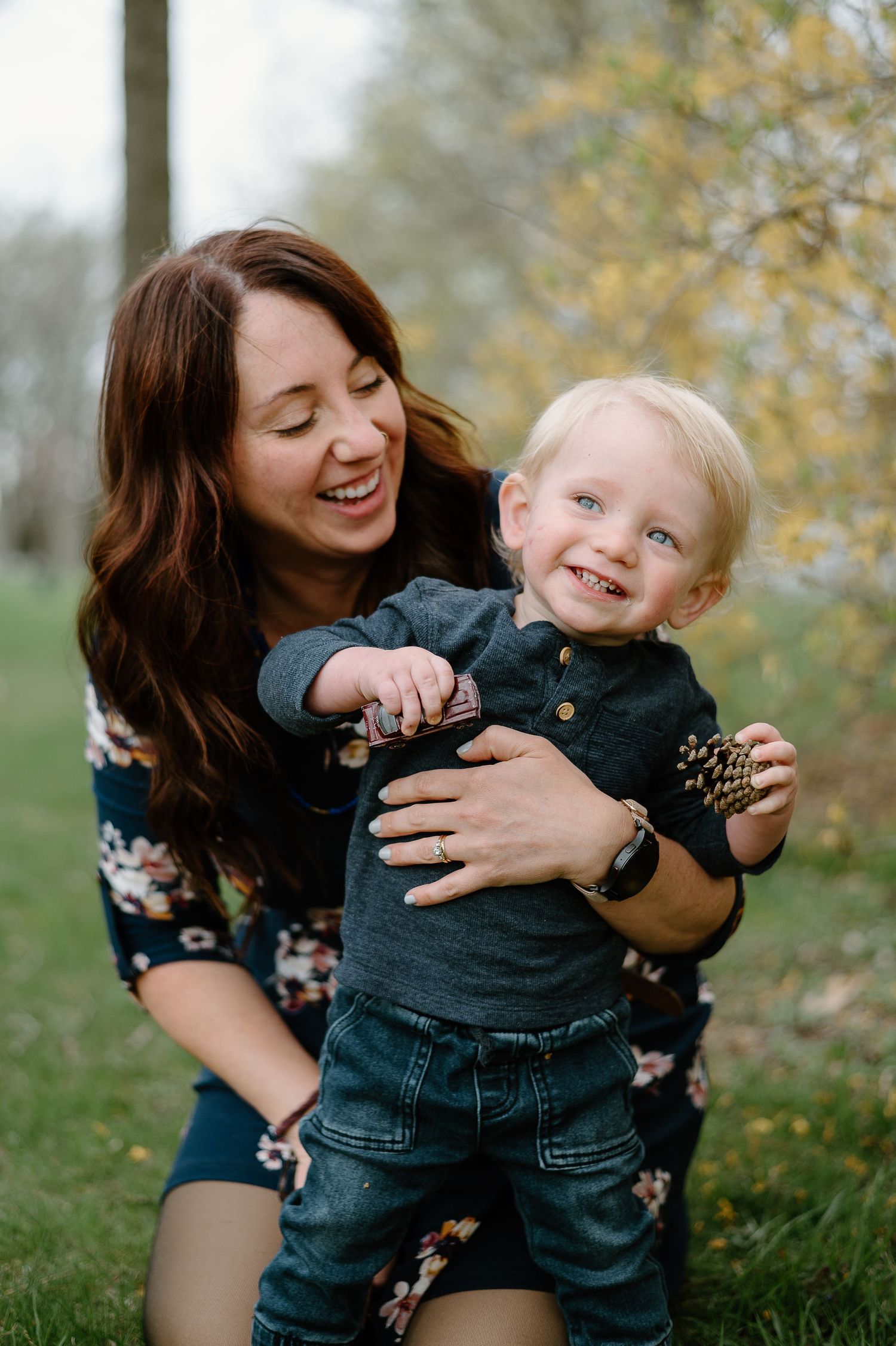 Joyful parent and giggling toddler playing together outdoors in autumn with fading yellow leaves in background.